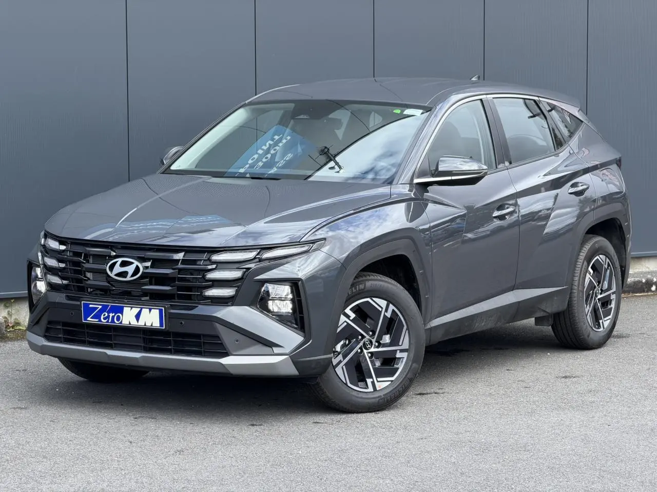 Hyundai Tucson 2026 Ecotronic Gray en 3/4 avant droit, avec jantes alliage et calandre noire distinctive.