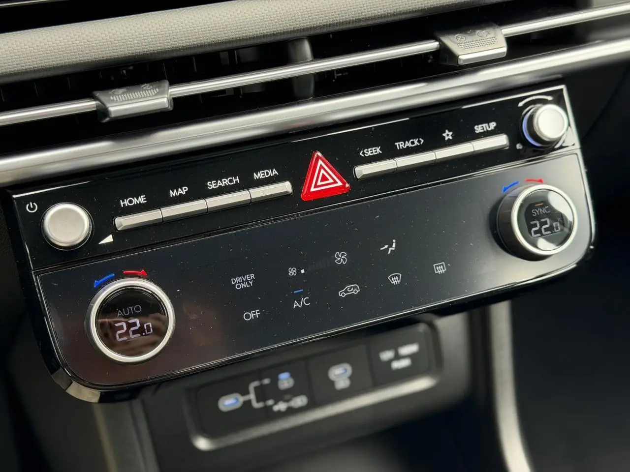 Gros plan sur la console centrale du Hyundai Tucson 2026, avec commandes climatisation digitale et boutons multifonctions noirs.