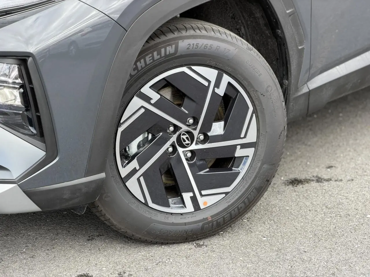 Gros plan sur la roue avant gauche d’un Hyundai Tucson Ecotronic Gray, jante alliage noire et argentée, pneu Michelin.