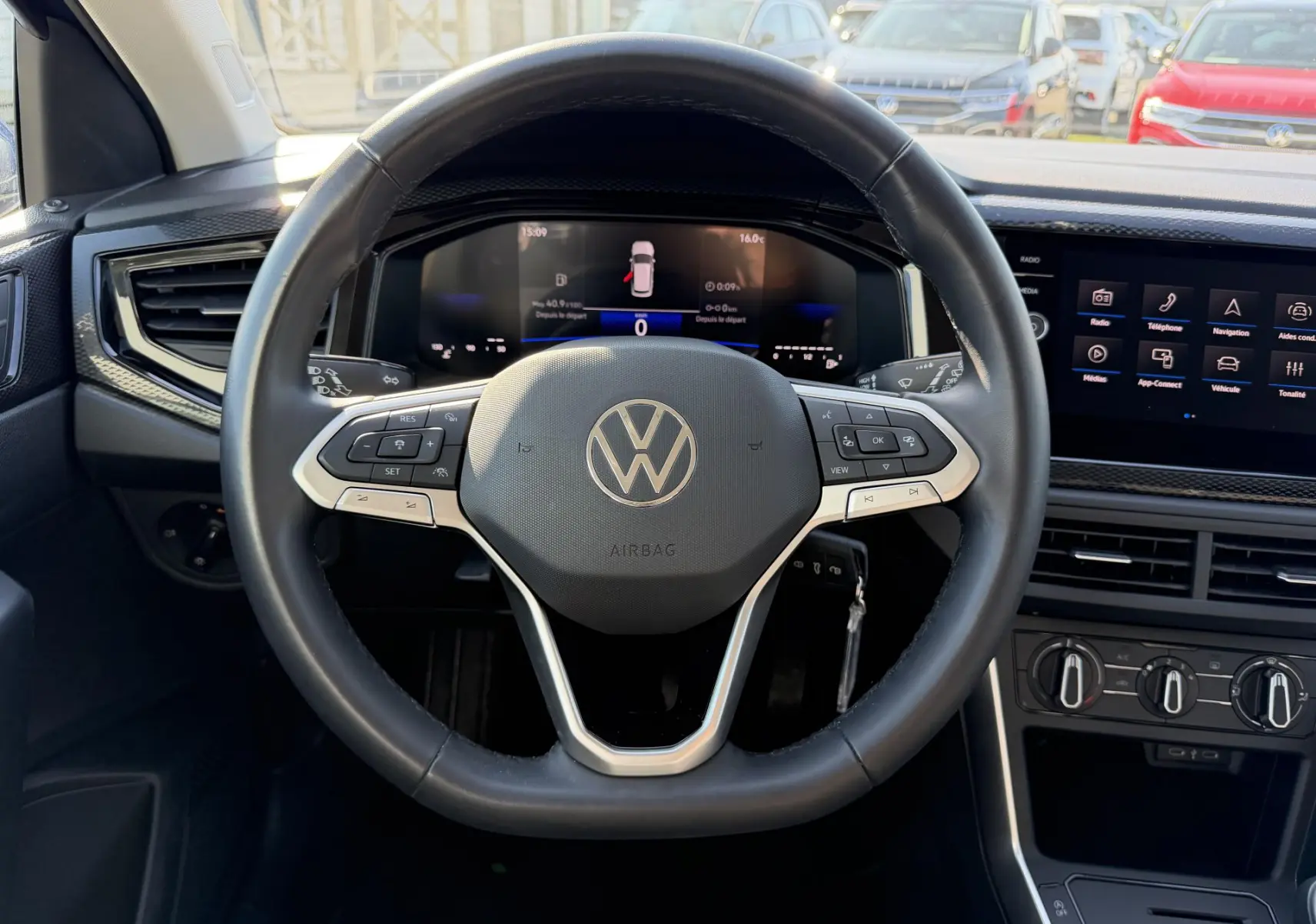Vue intérieure centrée sur le volant multifonction cuir du Volkswagen Taigo avec tableau de bord digital et écran tactile.