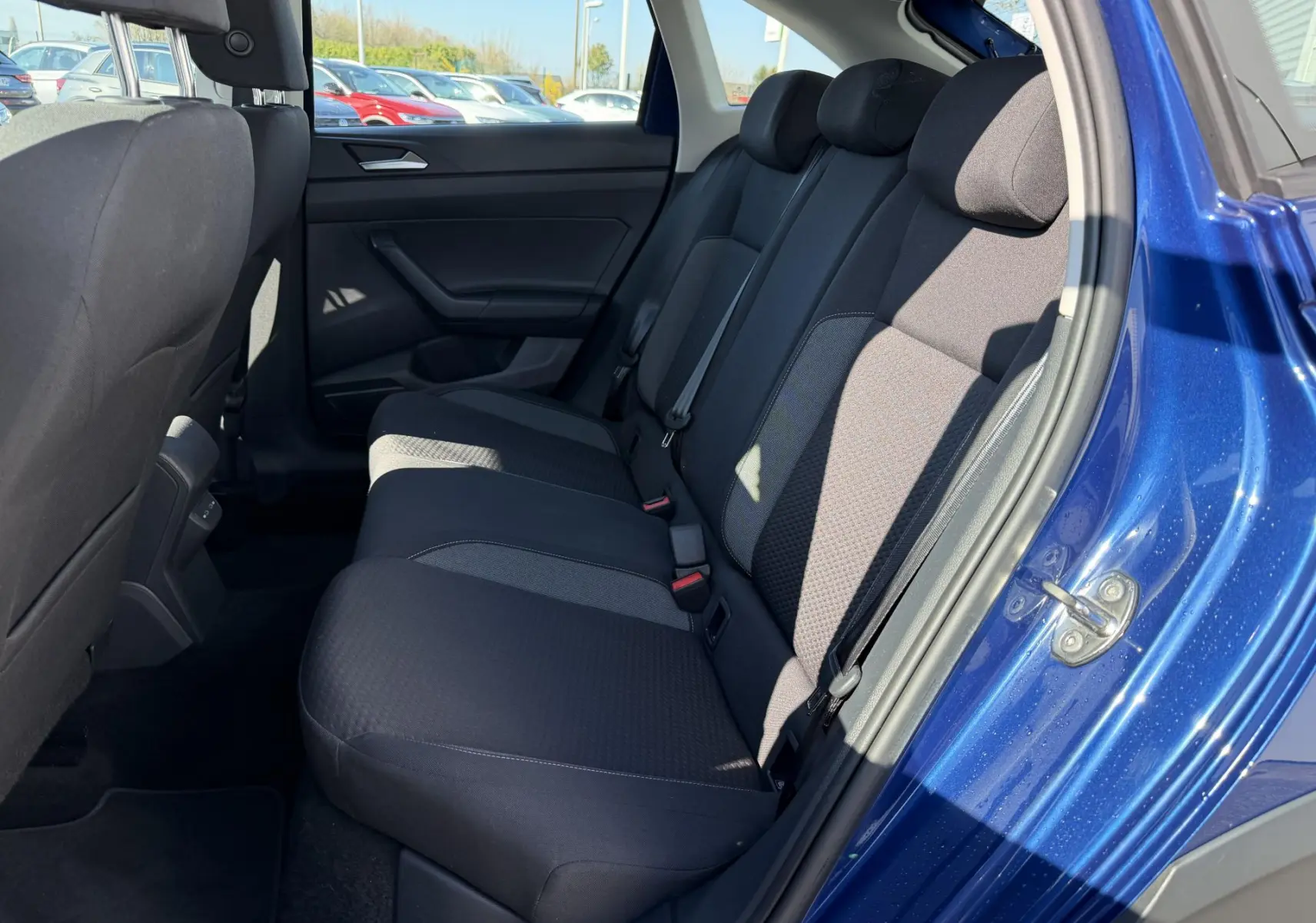 Vue intérieure côté droit des sièges arrière noirs du Volkswagen Taigo 2025 en bleu métallisé, porte ouverte.