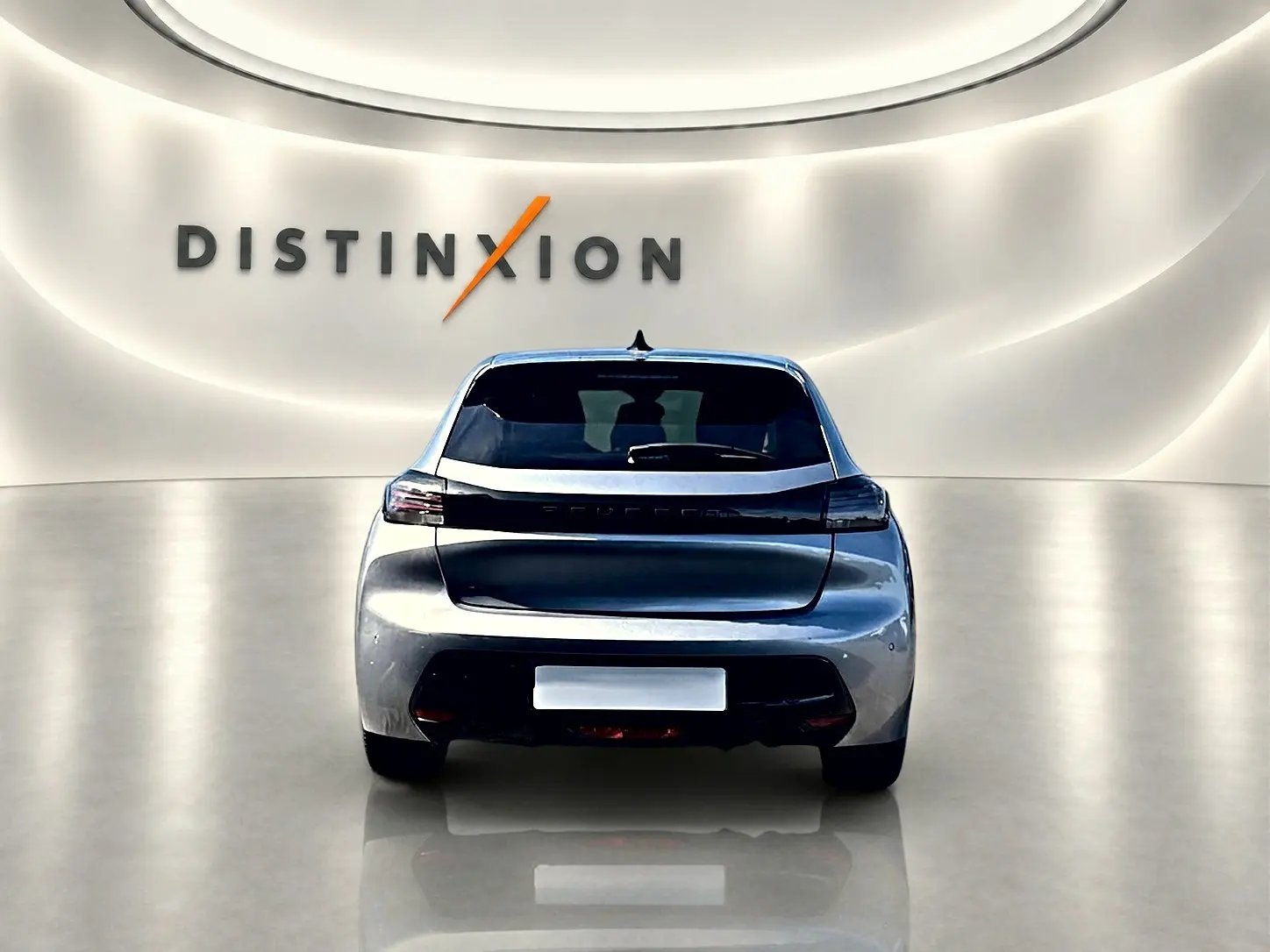 Vue arrière d'une Peugeot 208 1.2 100 Allure gris Artense dans un showroom lumineux avec logo Distinxion en arrière-plan.
