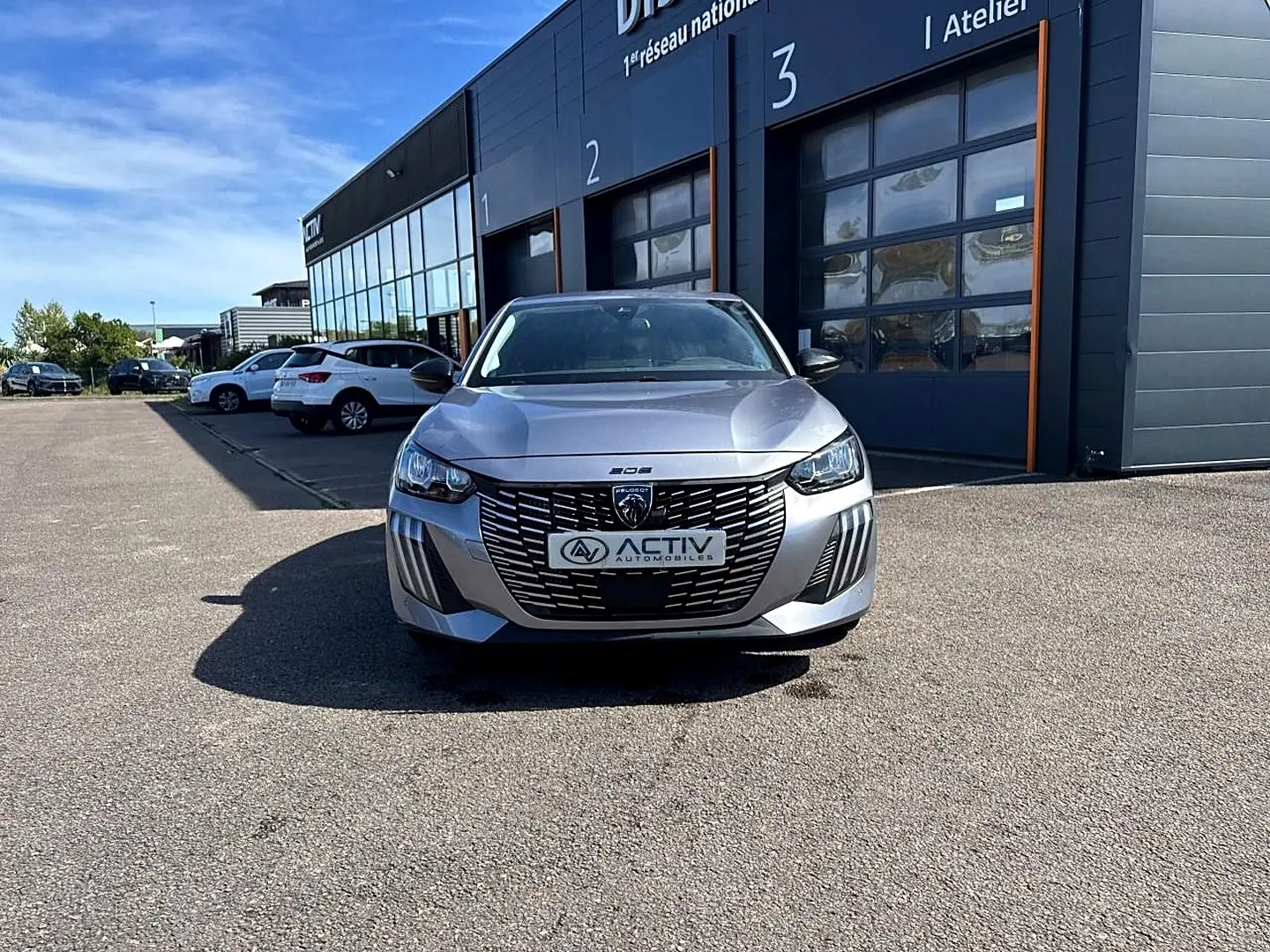 Peugeot 208 1.2 100 Allure gris Artense vue de face, avec calandre noire et phares LED marquants.
