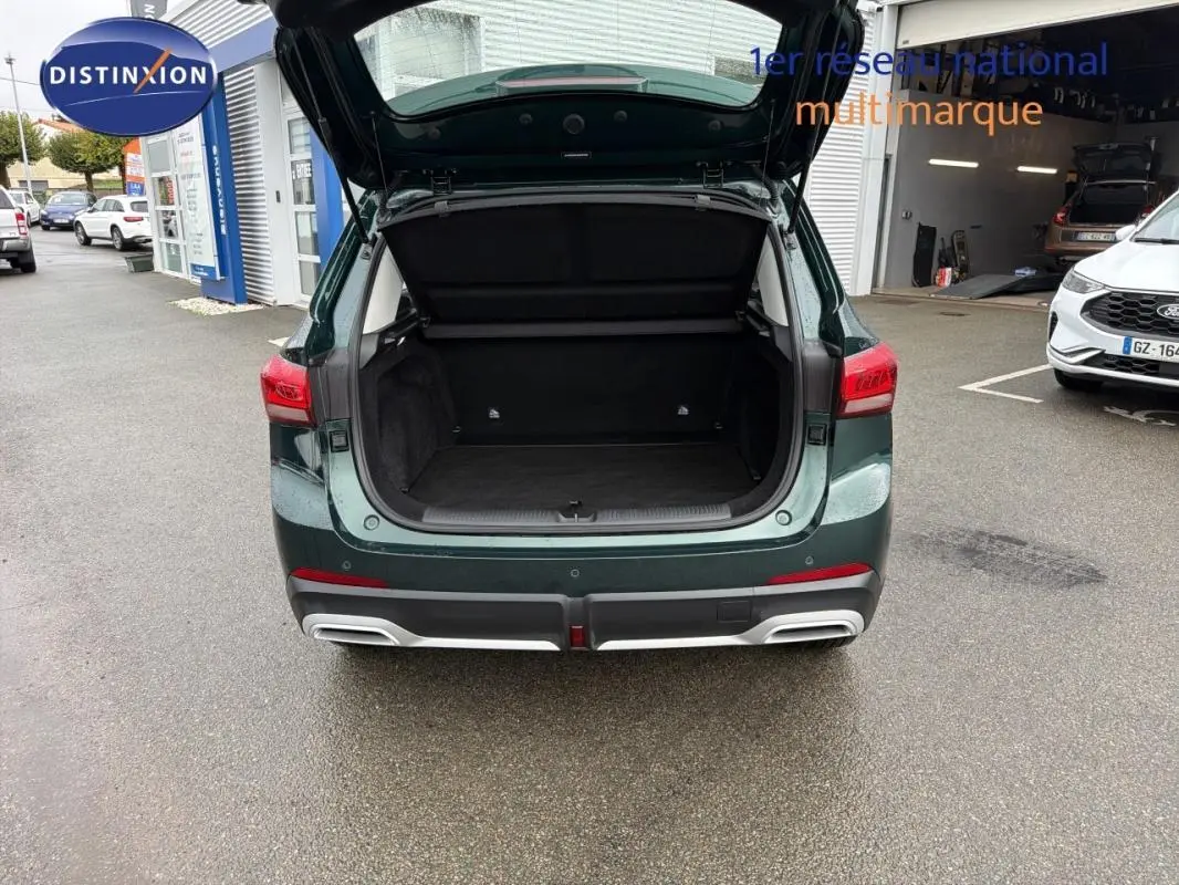 Vue arrière du MG MOTOR ZS vert foncé 2026 avec coffre ouvert, montrant l’espace de chargement vide.