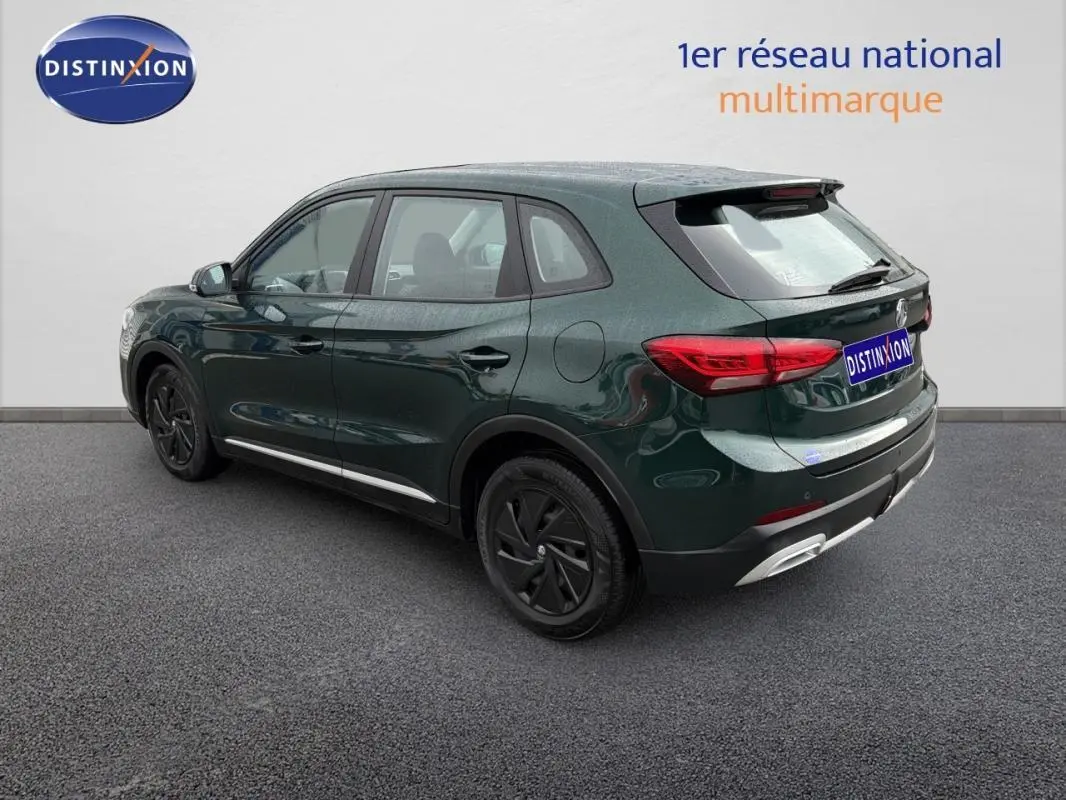 Vue 3/4 arrière droite d’un MG ZS vert foncé hybride avec jantes noires et détails chromés au niveau du pare-chocs.