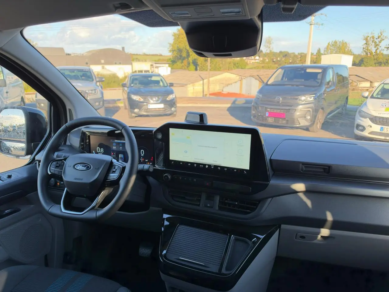 Vue intérieure du tableau de bord du Ford Transit Fourgon noir, avec écran tactile central et volant multifonction.