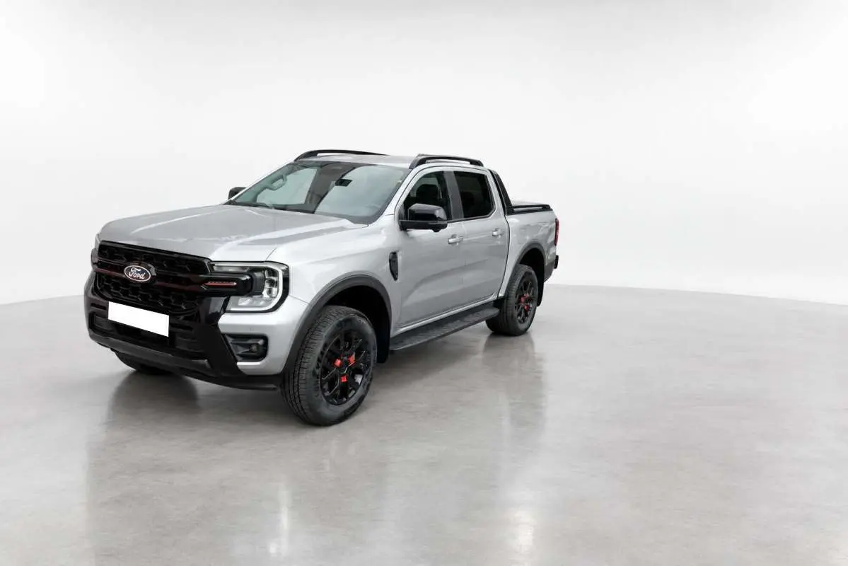 Ford Ranger Wildtrak gris iconic vu en 3/4 avant droit, avec jantes noires et détails rouges sur roues.