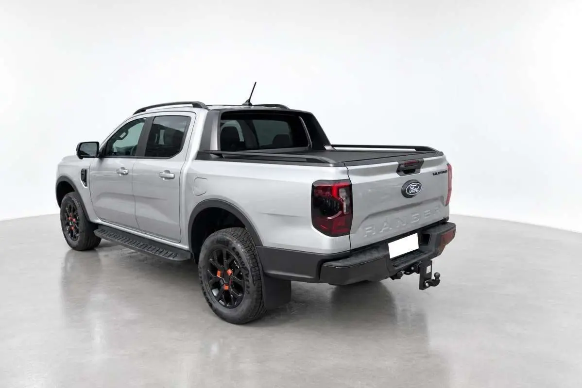 Ford Ranger Wildtrak gris iconic vu en 3/4 arrière droit avec barres de toit et attelage visible.