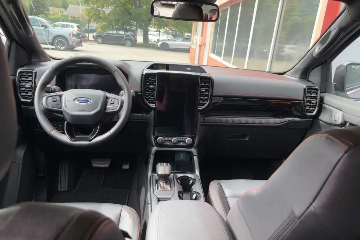 Vue intérieure avant du Ford Ranger Wildtrak 2026, tableau de bord noir avec écran vertical et volant multifonctions cuir.