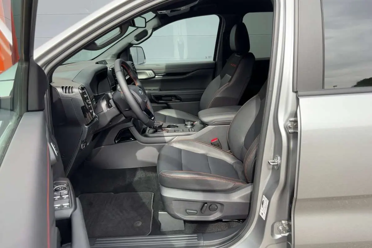 Vue intérieure côté conducteur du Ford Ranger gris iconic 2026, sièges en cuir noir avec surpiqûres orange et tableau de bord moderne.