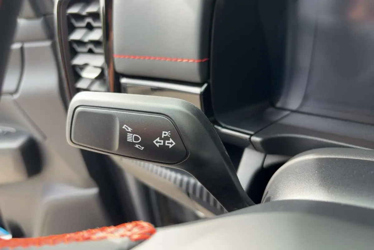 Gros plan sur la commande de clignotant et feux du Ford Ranger Wildtrak Plus 2026, intérieur noir avec surpiqûres rouges.