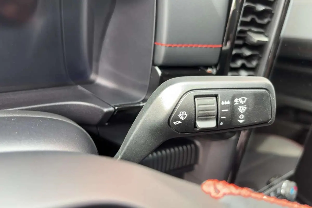 Gros plan sur la commande des essuie-glaces dans l’habitacle du Ford Ranger gris iconic, avec surpiqûres rouges visibles.