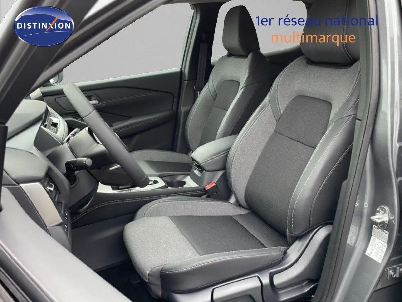 Vue intérieure côté conducteur du Nissan Qashqai 2025 gris squale métal, sièges tissu et cuir avec coutures contrastées.