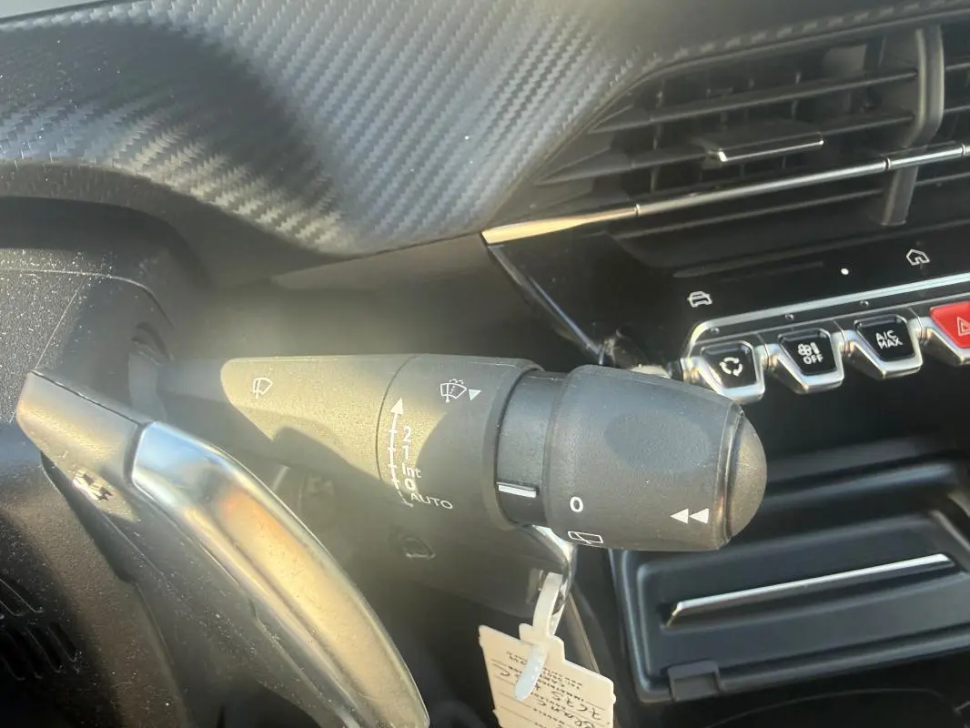 Gros plan sur la commande d’essuie-glace côté gauche du tableau de bord du Peugeot 208 Hybrid blanc 2024.