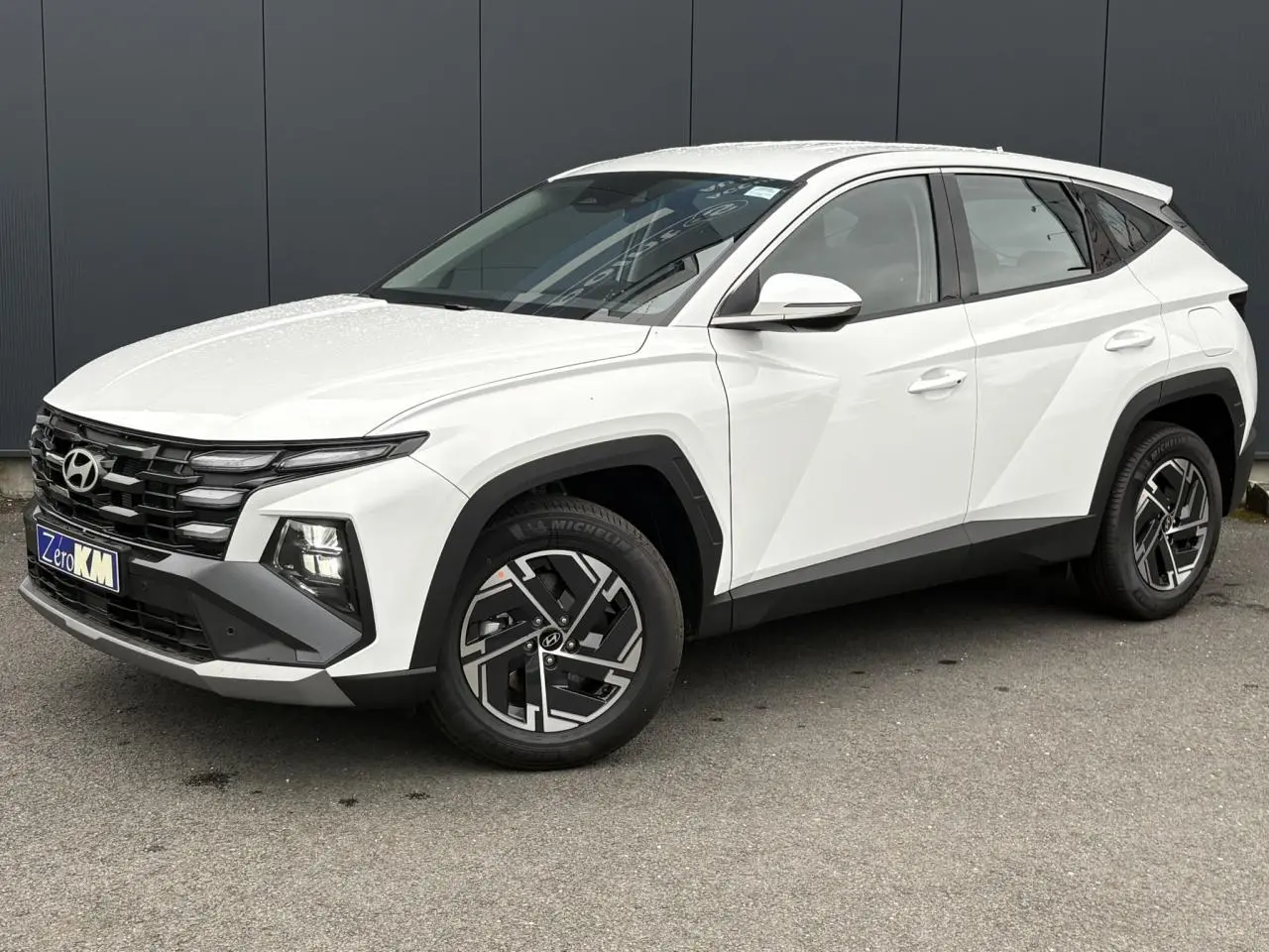 Vue 3/4 avant droite du Hyundai Tucson 2026 blanc Serenity avec jantes alliage 17 pouces et calandre noire distinctive.