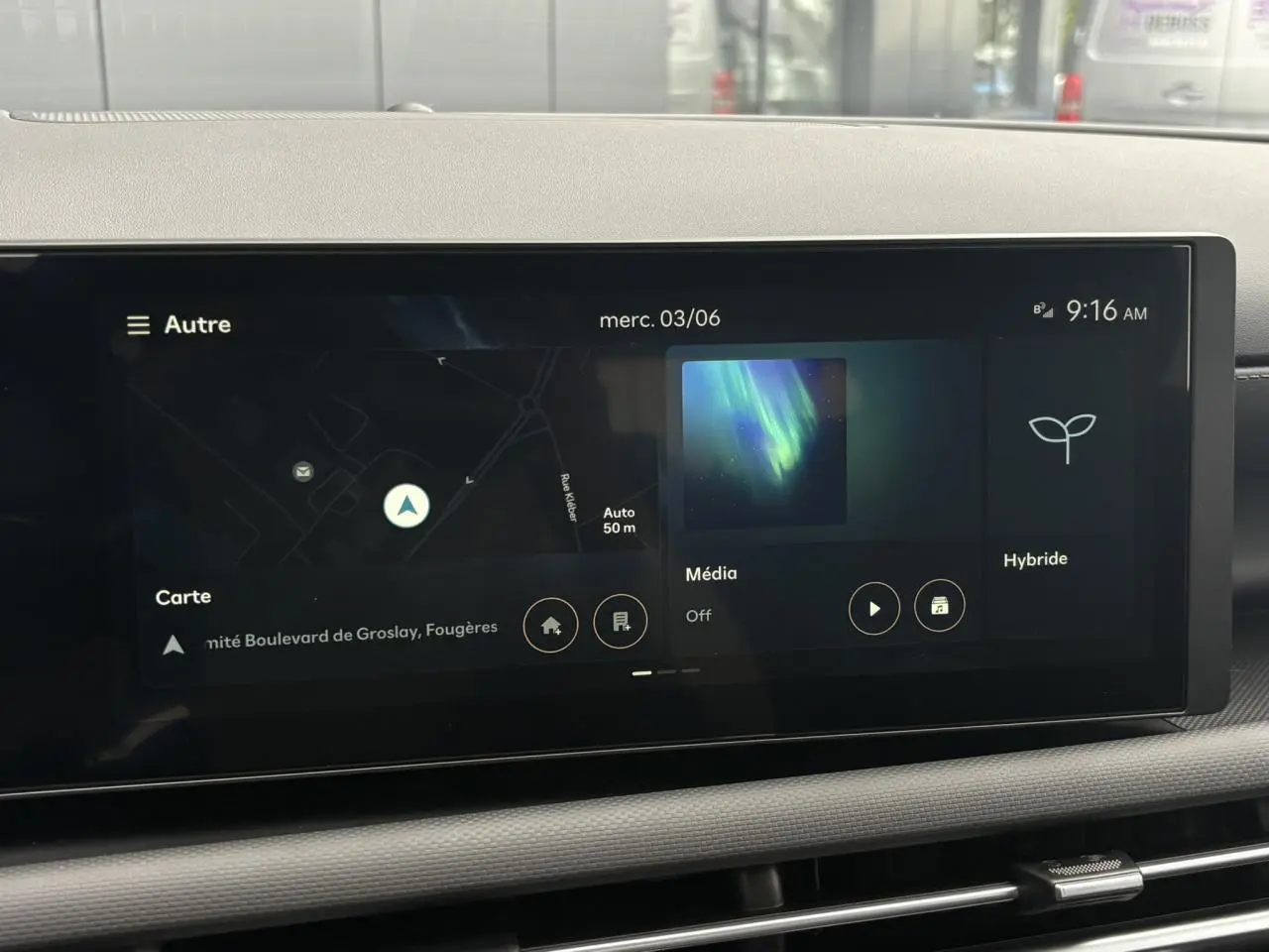Écran tactile multimédia du Hyundai Tucson 2026 affichant navigation, média et mode hybride, vue intérieure centrale.