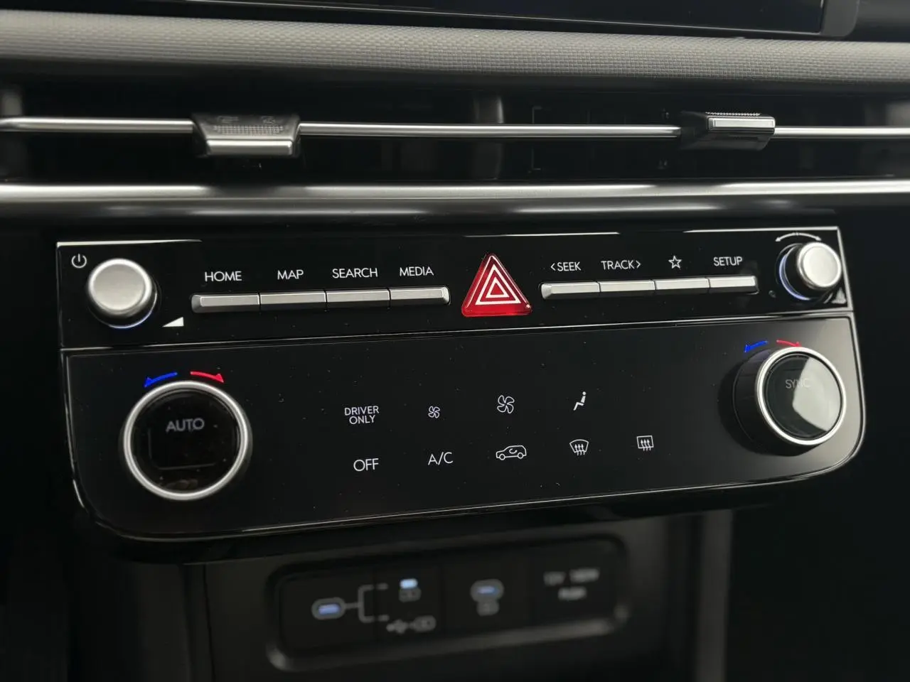 Gros plan sur la console centrale noire du Hyundai Tucson 2026, avec commandes climatisation et multimédia visibles.