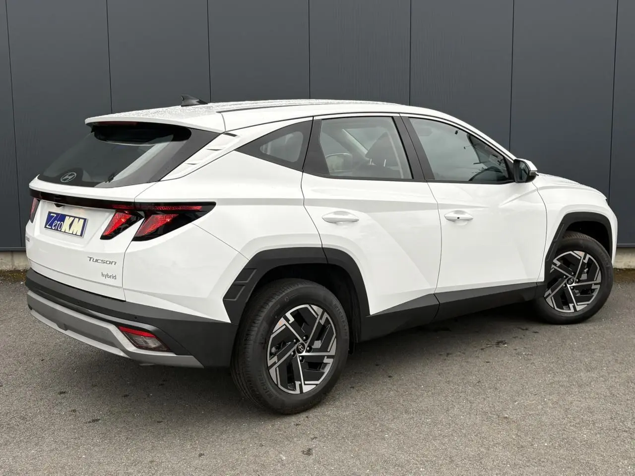 Vue 3/4 arrière droite d’un Hyundai Tucson Serenity White avec jantes alliage 17’’ et détails noirs contrastants.