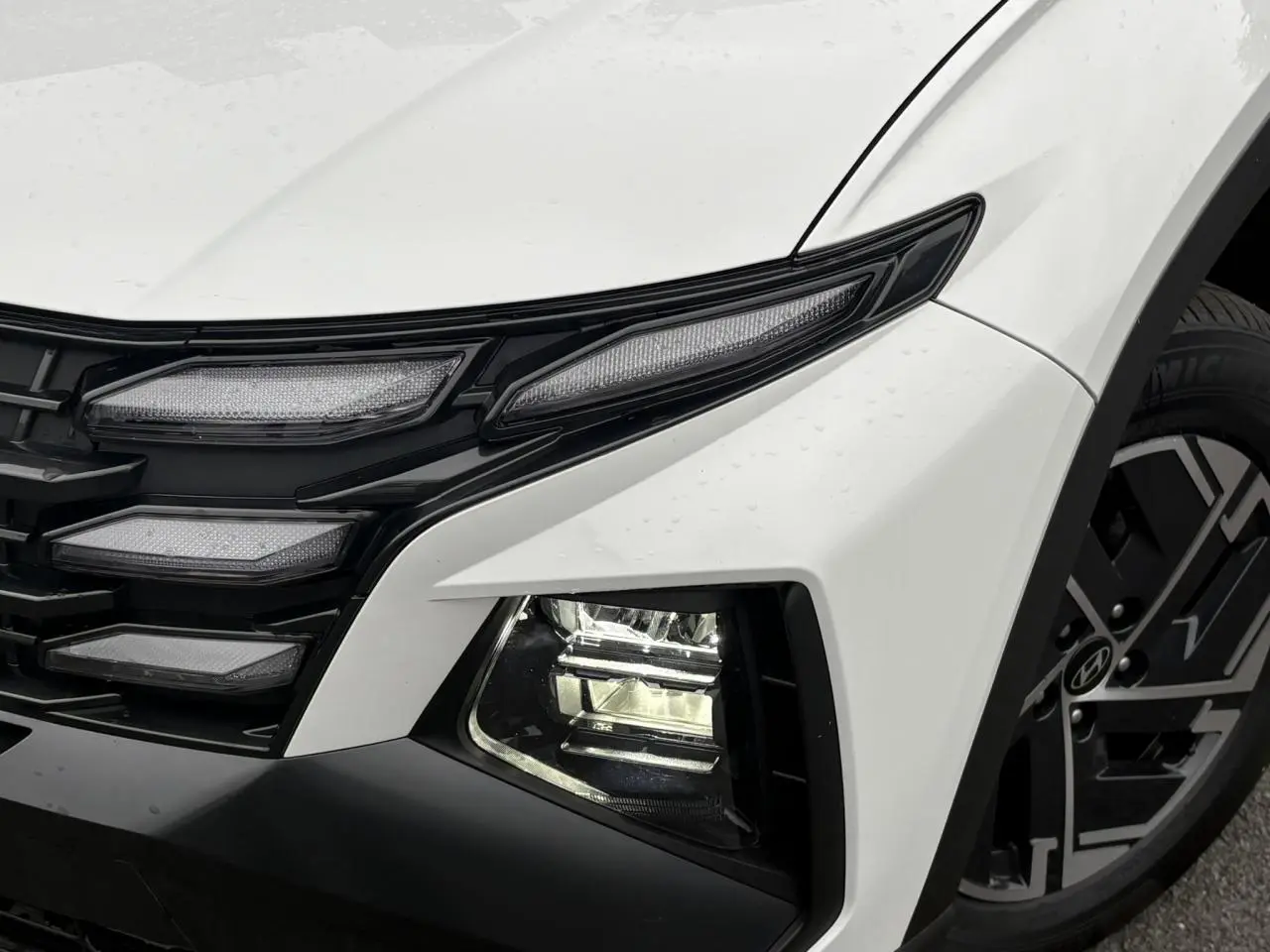 Gros plan sur l'avant droit du Hyundai Tucson blanc Serenity, avec ses phares LED et jante alliage 17 pouces.