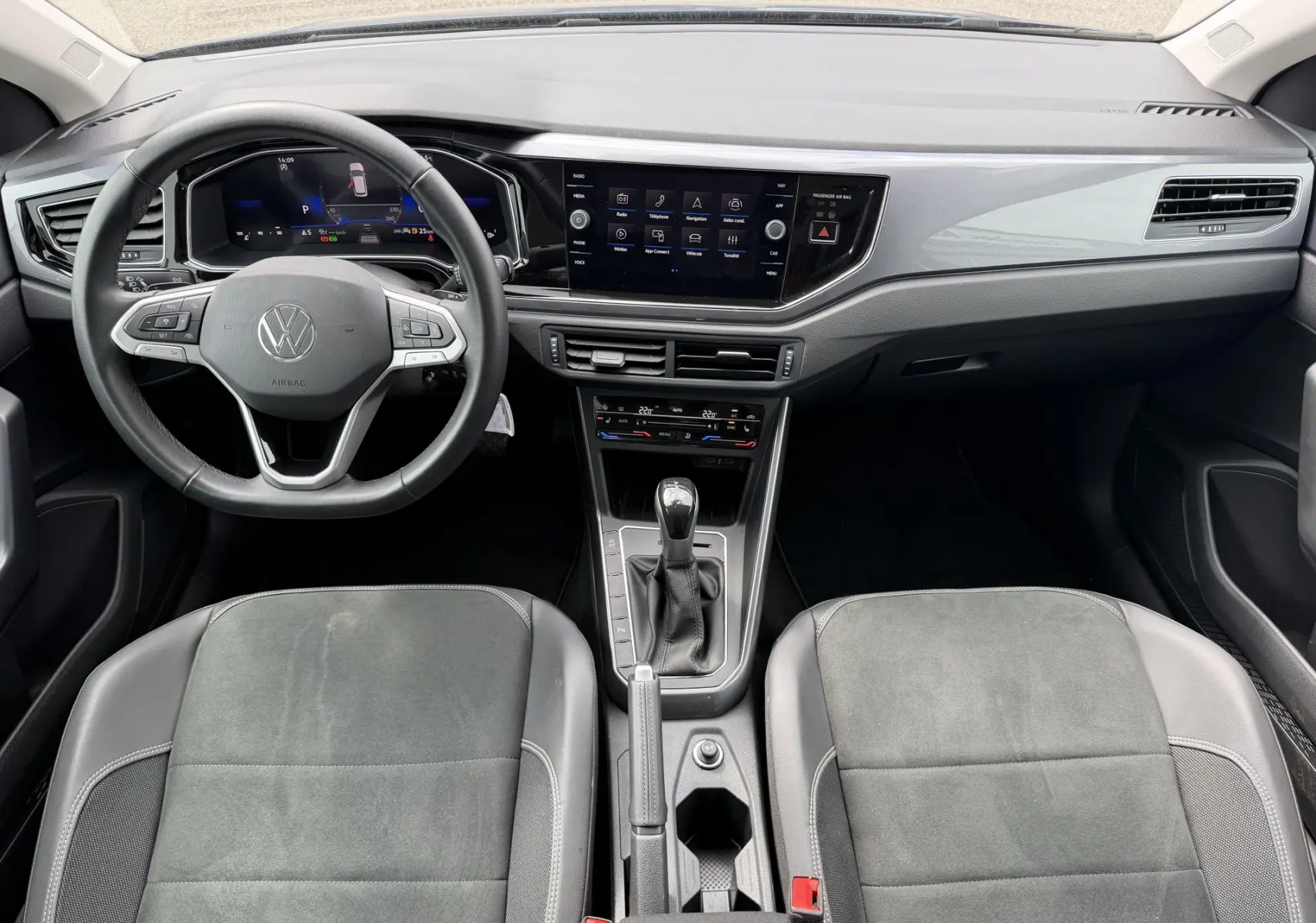 Vue intérieure avant de la Volkswagen Polo 2025, tableau de bord noir avec écran tactile et volant cuir multifonctions.