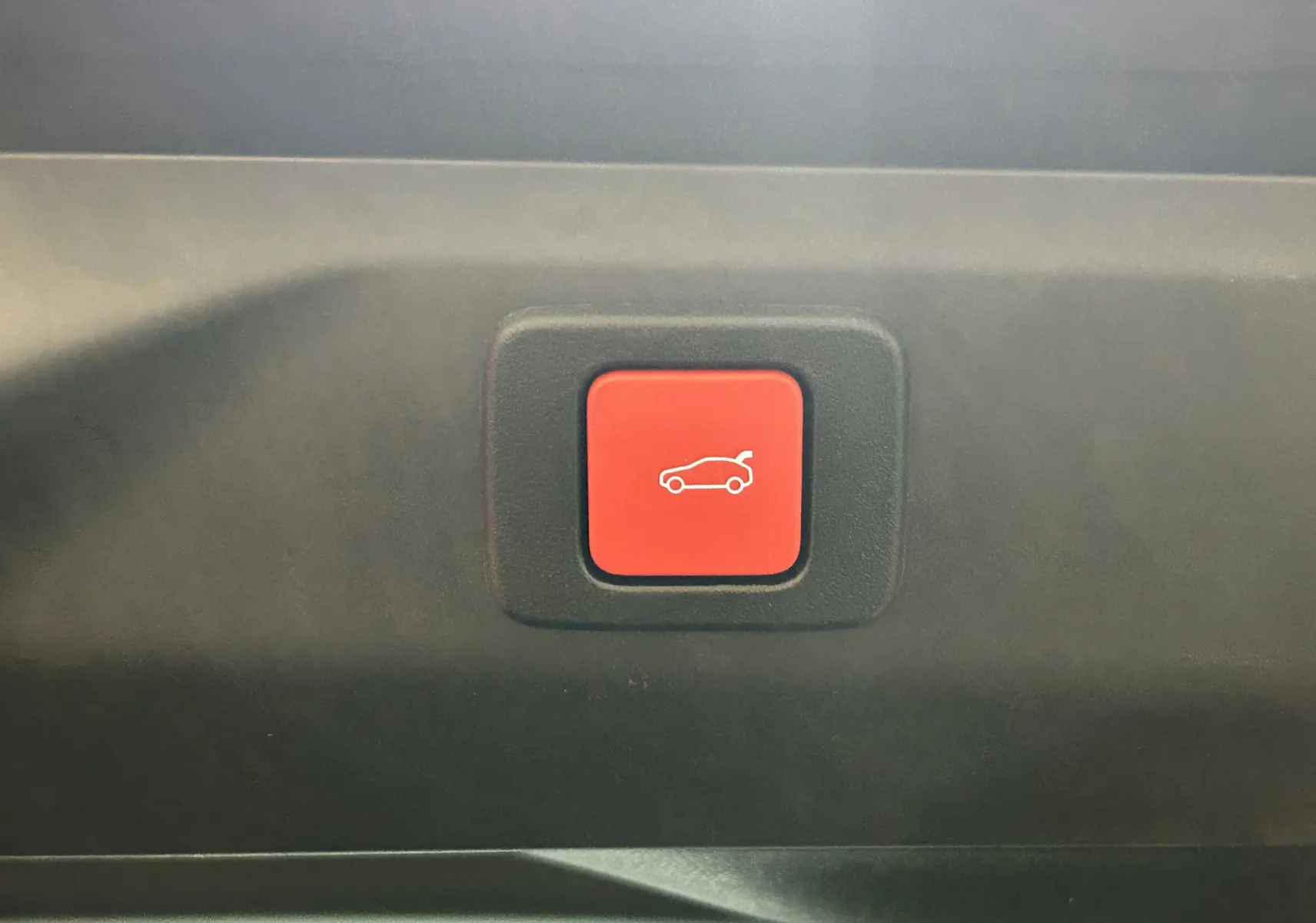Bouton rouge d'ouverture électrique du hayon sur le coffre d'un Peugeot 3008 blanc Okenite 2025.