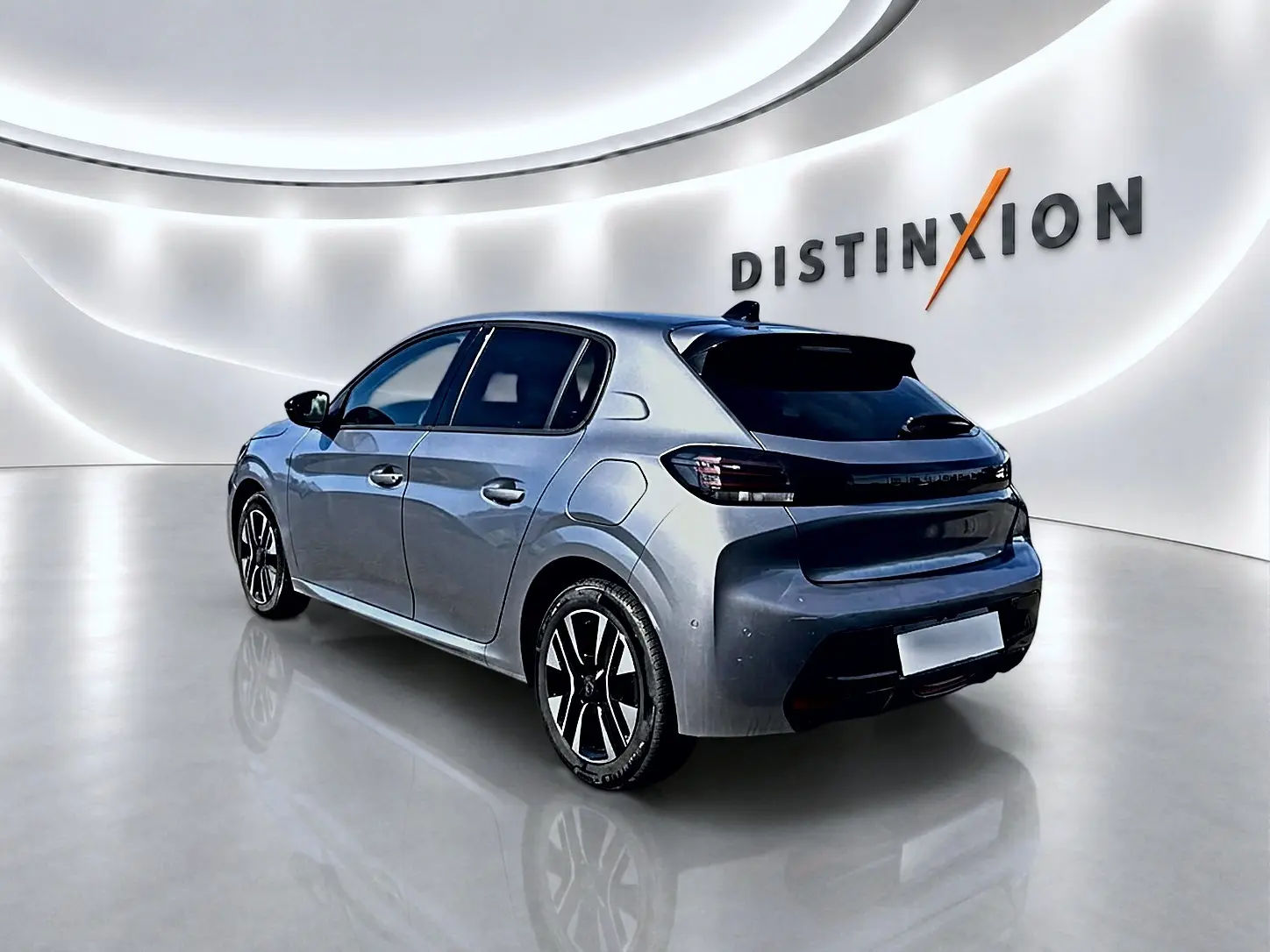 Peugeot 208 gris artense vue 3/4 arrière droit dans un showroom lumineux avec jantes alliage noires.