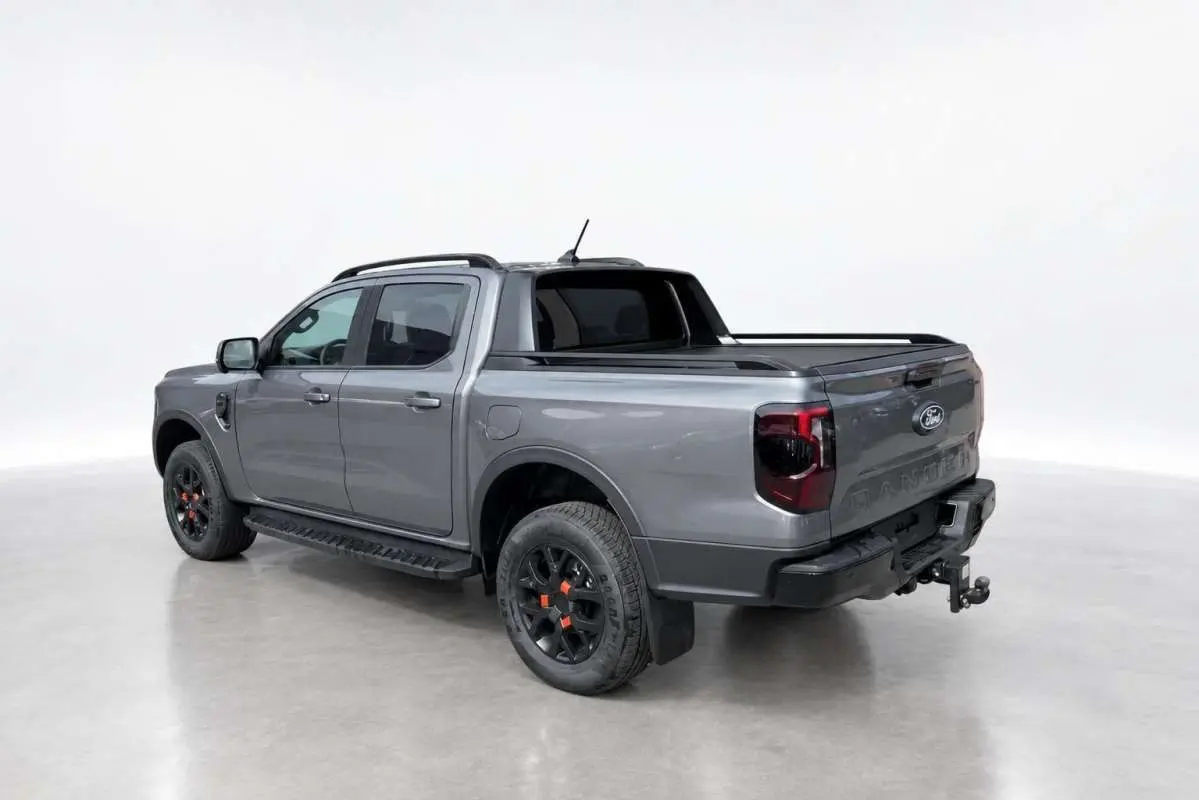 Ford Ranger Wildtrak gris carbone vu en 3/4 arrière droit, avec jantes noires et attelage visible.