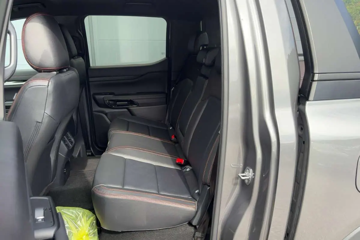 Vue intérieure côté droit sur la banquette arrière en cuir noir avec surpiqûres orange du Ford Ranger gris carbone 2026.