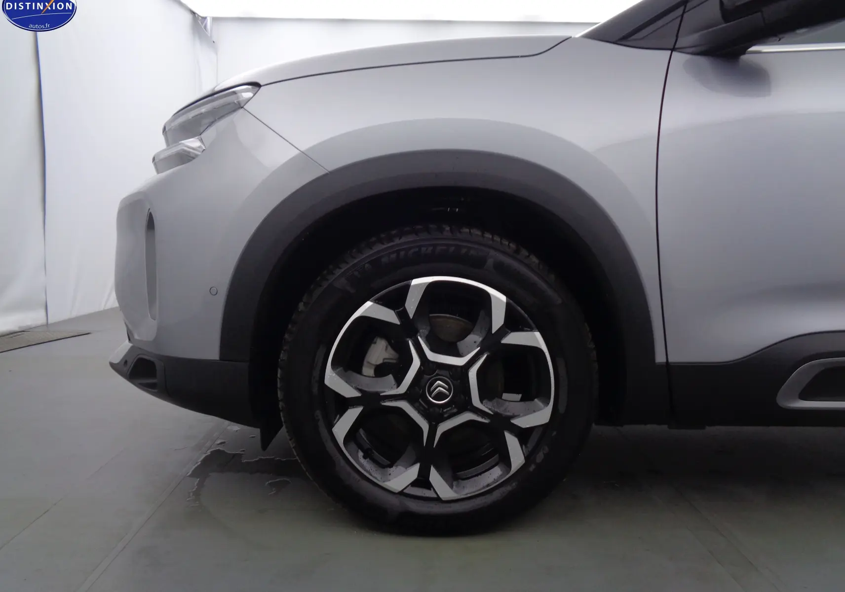 Gros plan sur la roue avant gauche d'un Citroën C5 Aircross gris Artense métal avec jante alliage noire et argent.