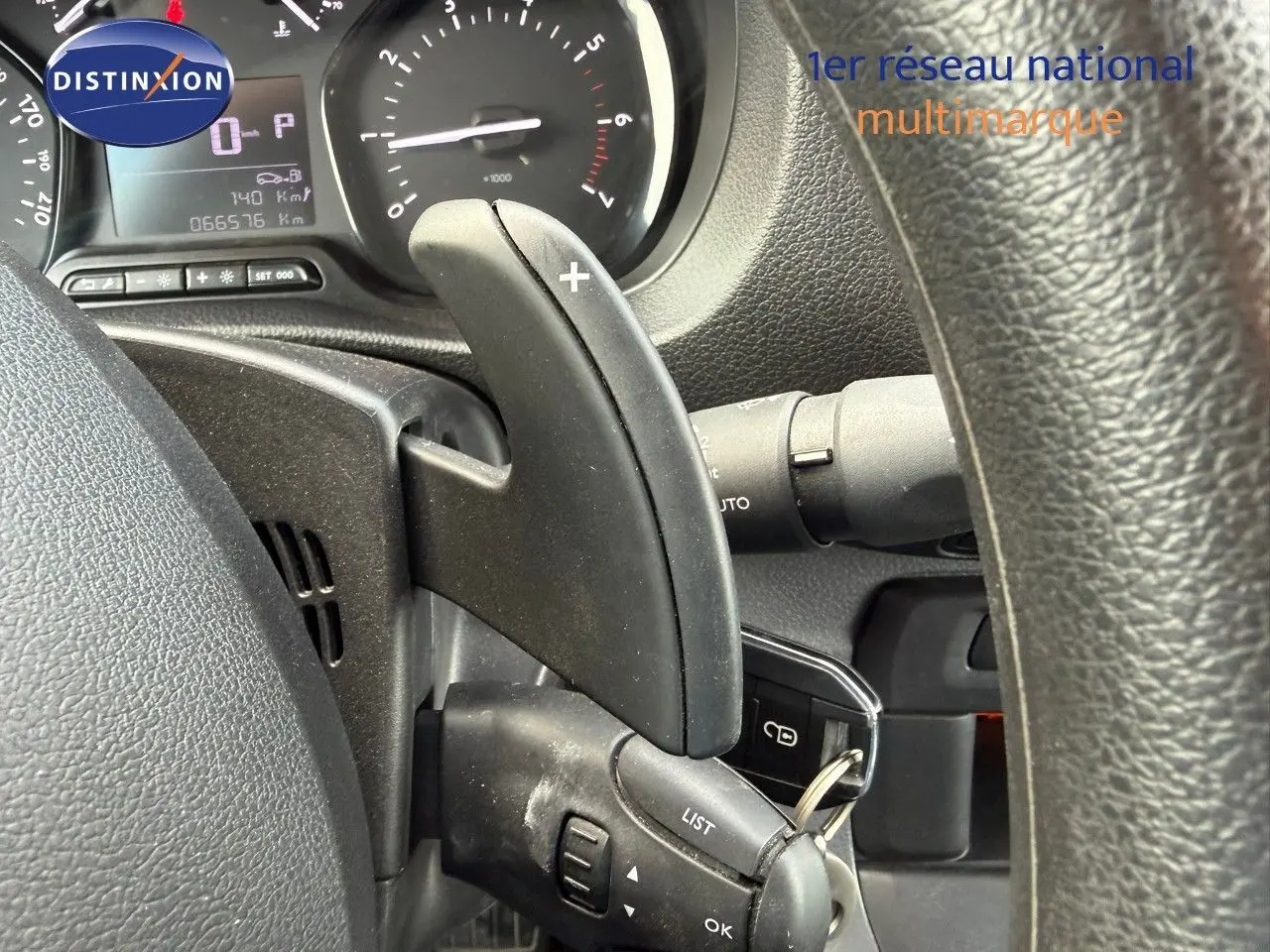 Gros plan sur la commande de boîte automatique au volant d'un Opel Vivaro Fourgon gris Pierre de Lune, tableau de bord visible.