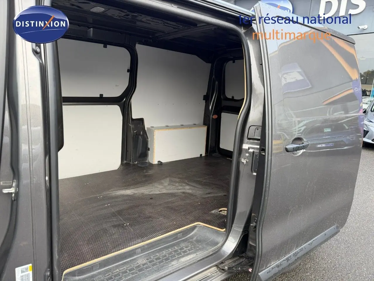 Vue côté droit du fourgon Opel Vivaro M 2.0 CDTI 180 BVA Business gris Pierre de Lune métallisé avec porte coulissante ouverte montrant l'espace de chargement vide.