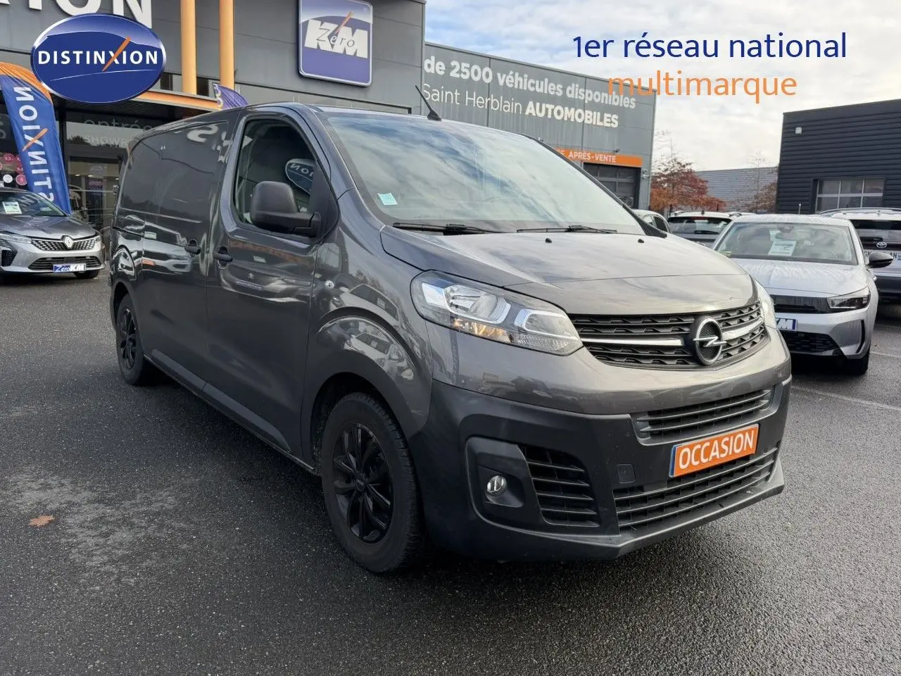 Opel Vivaro Fourgon gris Pierre de Lune métallisé vu en 3/4 avant droit avec calandre noire et jantes foncées.