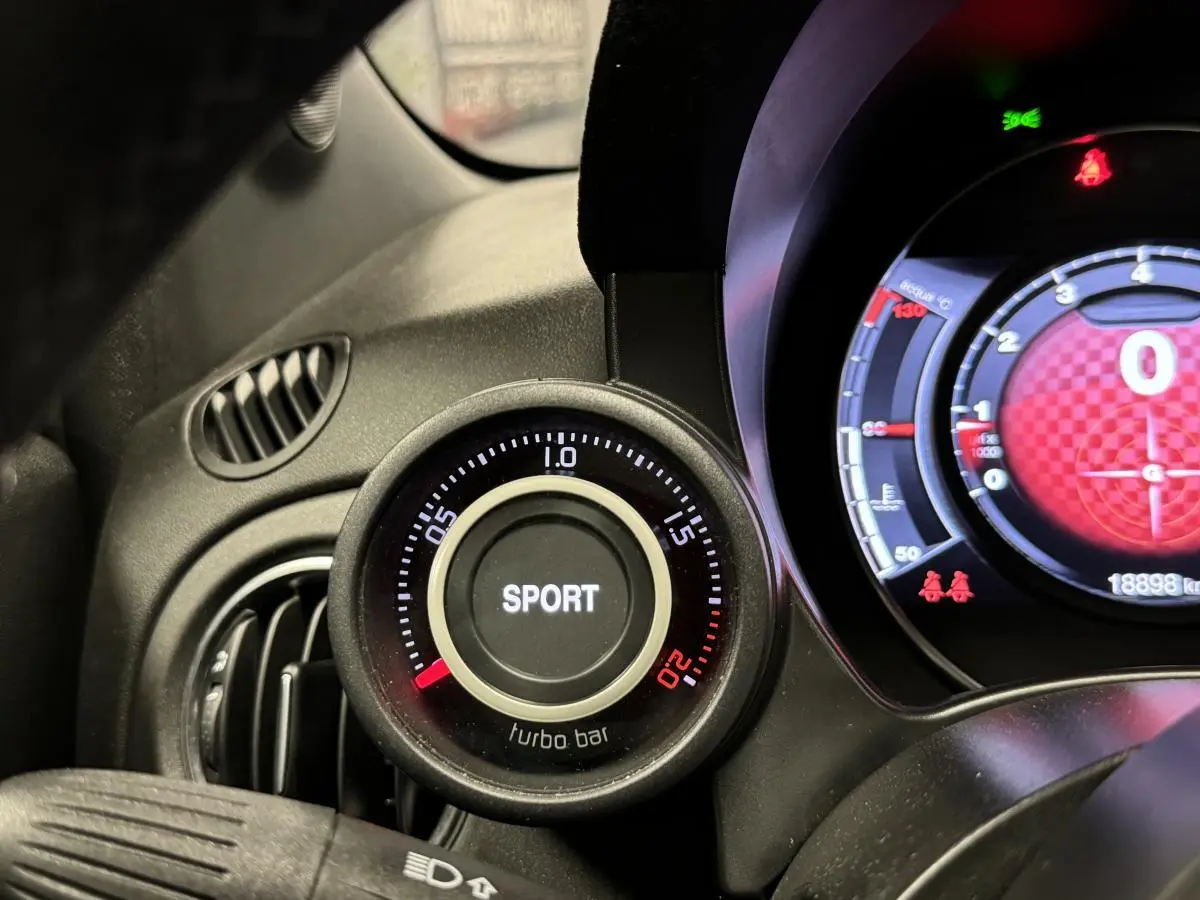 Gros plan sur le manomètre turbo avec mode Sport de l'Abarth 595 Competizione noir, tableau de bord partiellement visible.