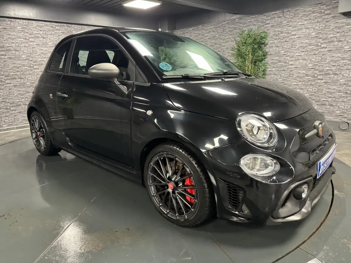 Vue 3/4 avant droite d'une ABARTH 595 Competizione noire avec jantes noires et étriers de frein rouges.