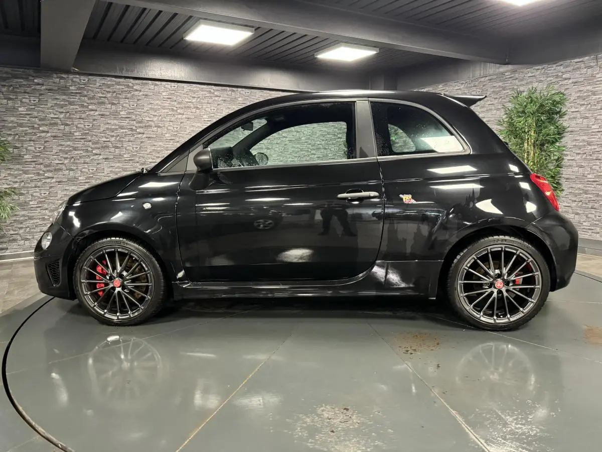 Profil côté gauche de l'Abarth 595 Competizione noire avec jantes alliage 17 pouces et étriers de frein rouges visibles.