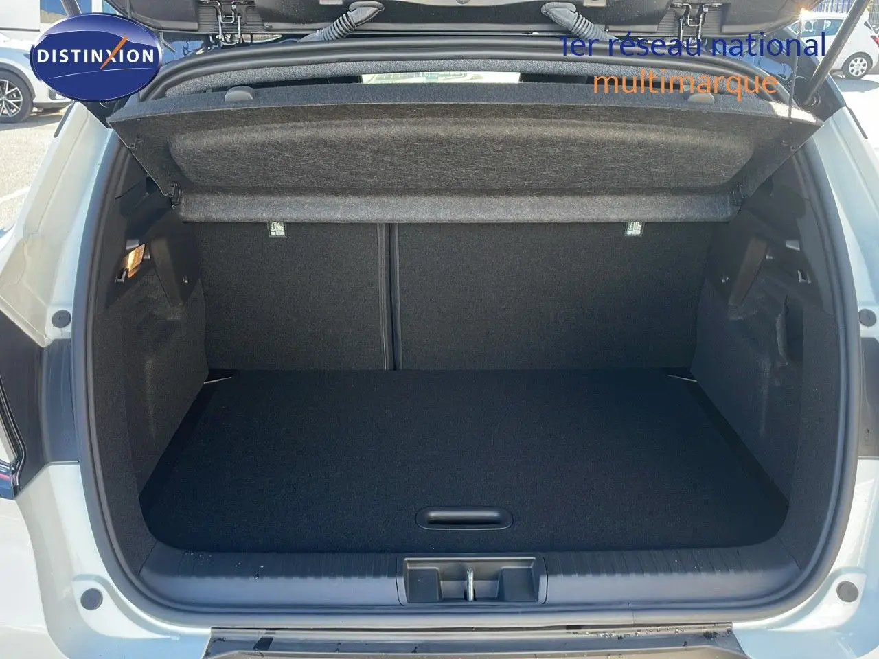 Coffre ouvert du Renault Captur E-Tech blanc nacré avec toit noir, vue arrière montrant l'espace de chargement vide.
