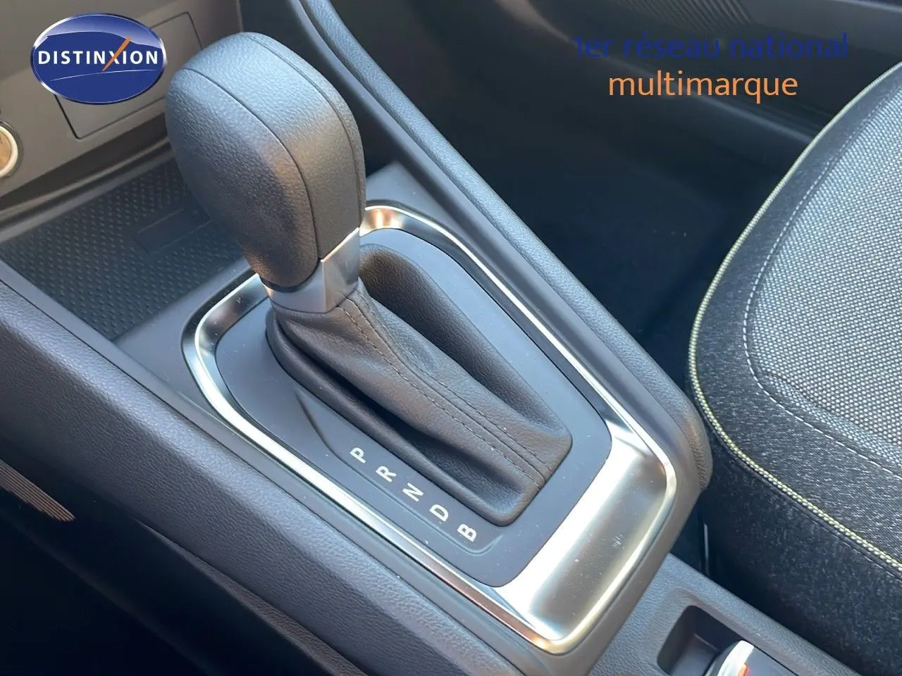 Le levier de vitesses automatique en cuir noir du Renault Captur E-Tech Hybrid 2025, avec console et siège tissu gris.