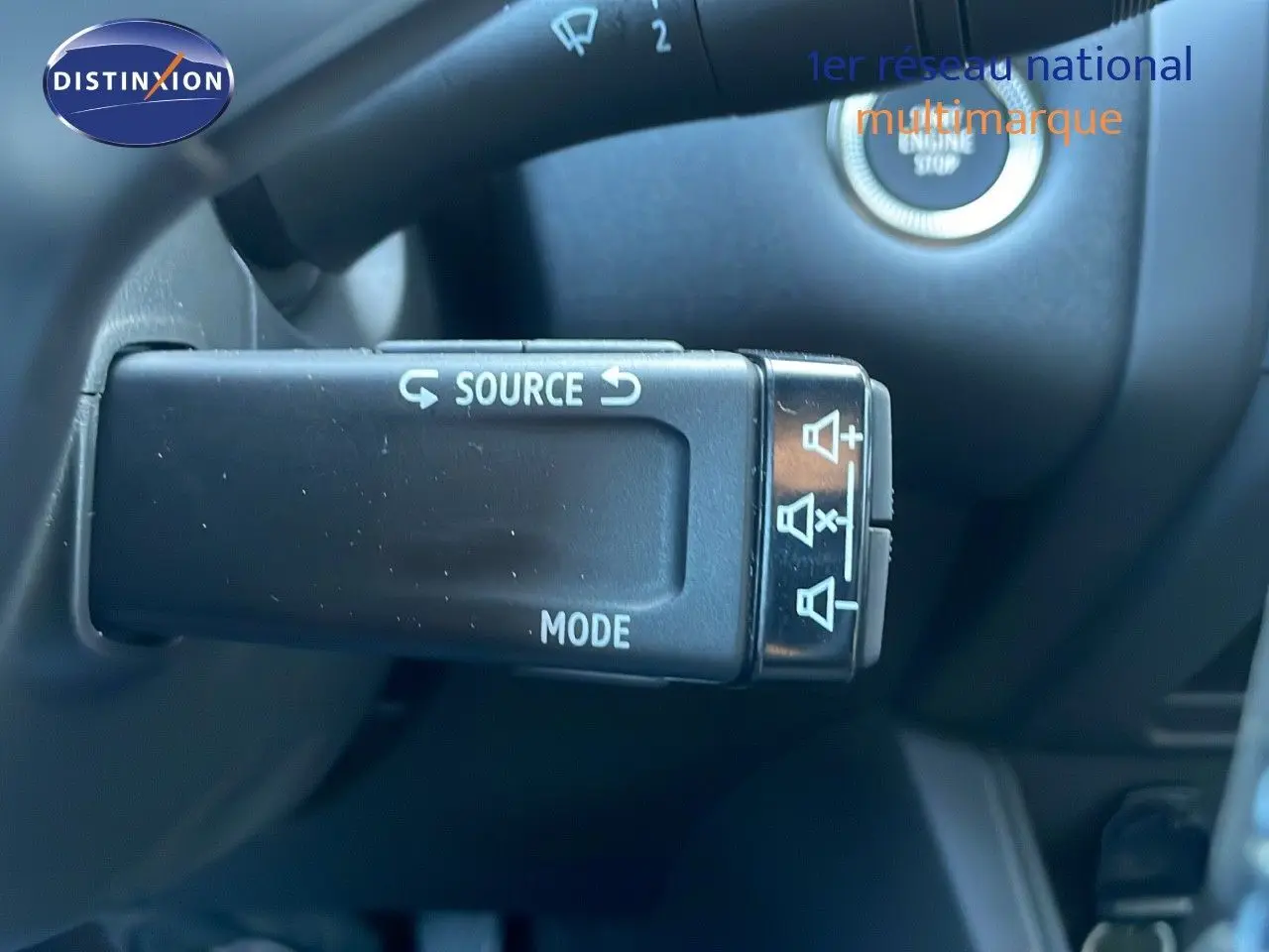 Gros plan sur la commande au volant du Renault Captur blanc nacré, avec bouton source et mode visibles.