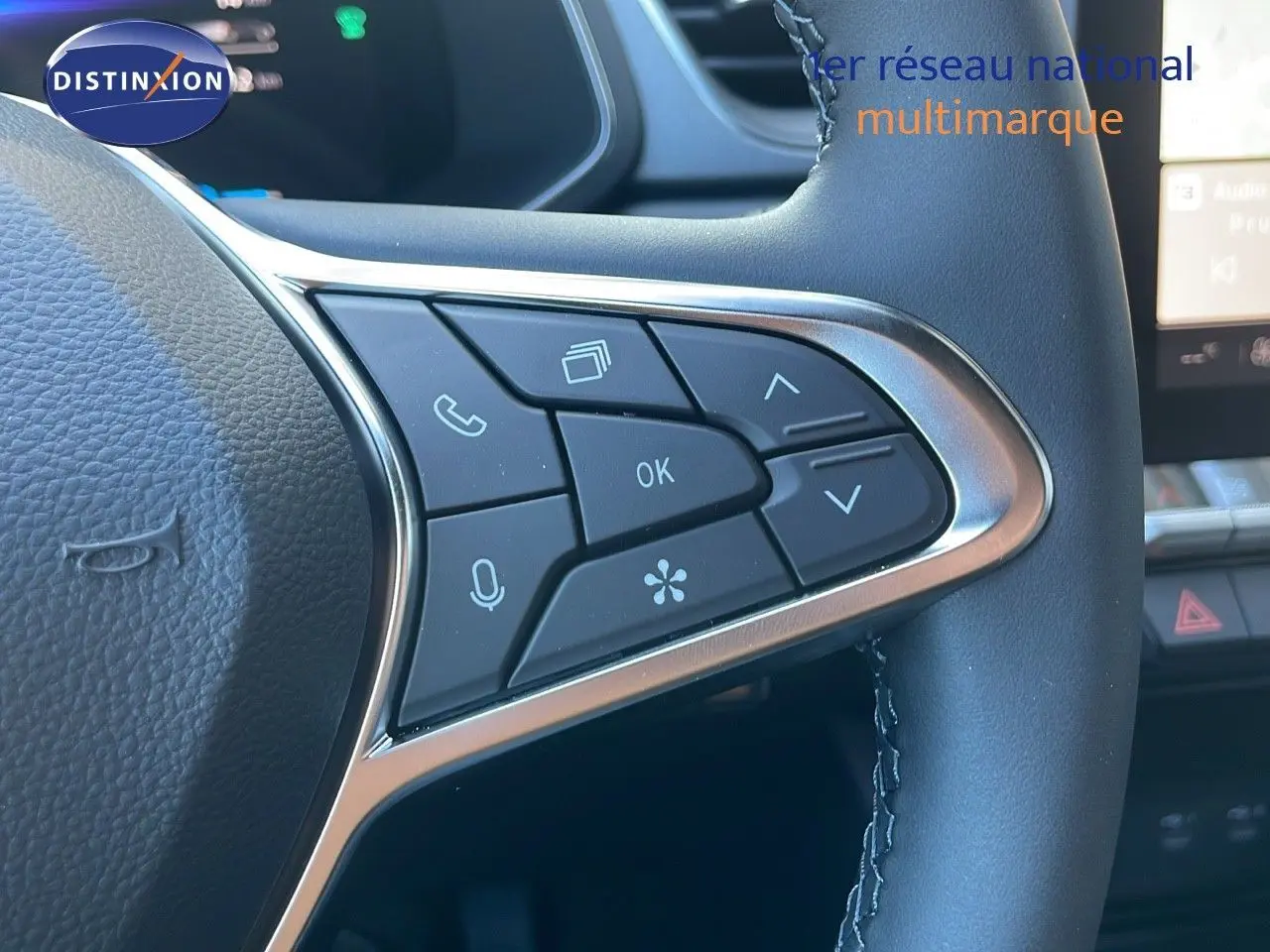 Gros plan sur les commandes au volant du Renault Captur E-Tech blanc nacré, mettant en valeur les boutons multifonctions.