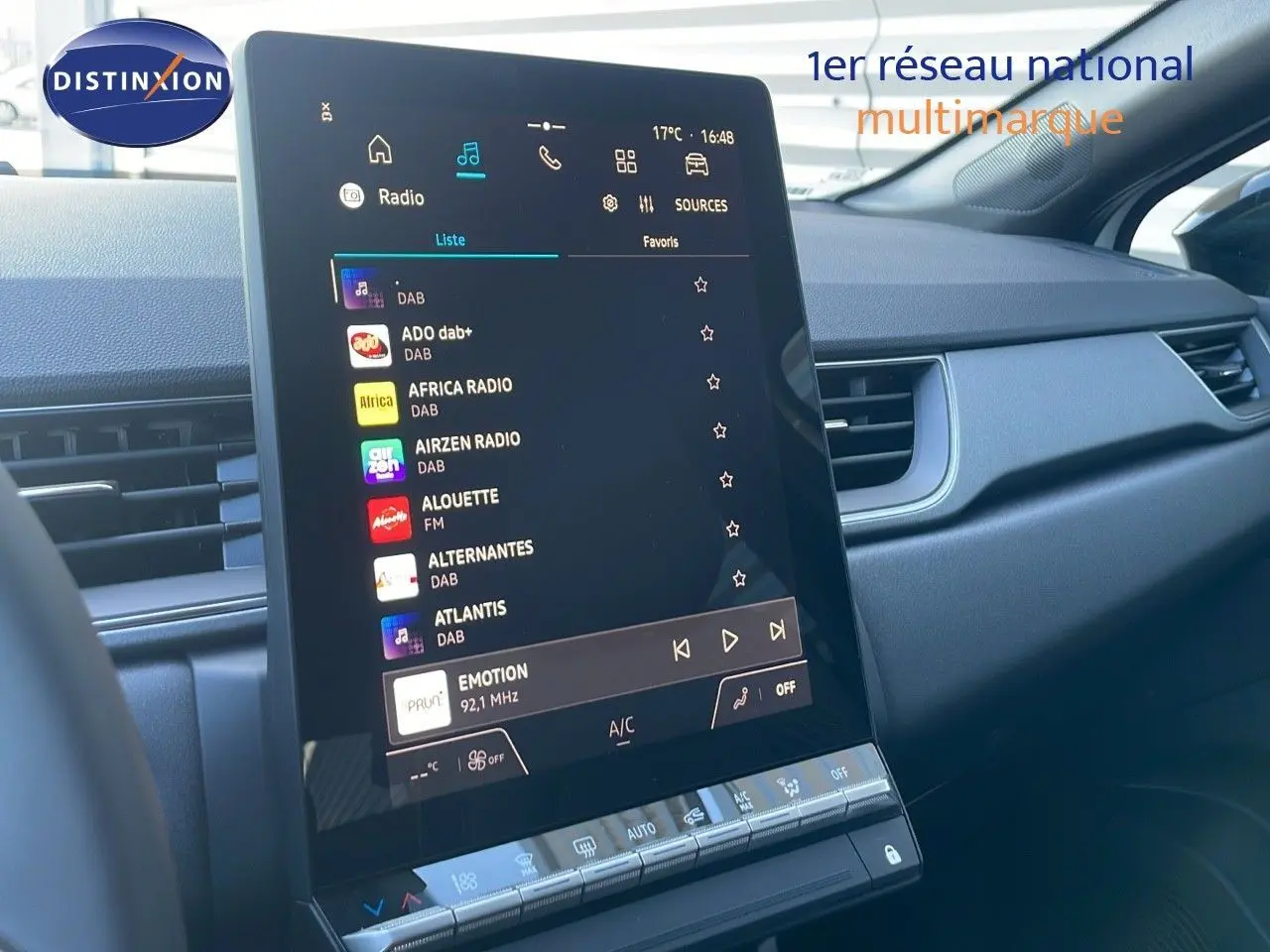 Écran central tactile affichant la liste des radios dans l'habitacle du Renault Captur blanc nacré toit noir, vue de face.