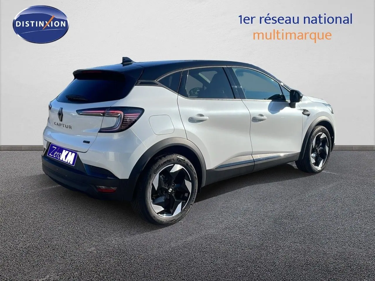 Vue 3/4 arrière droite d'un Renault Captur blanc nacré avec toit noir et jantes bicolores modernes.