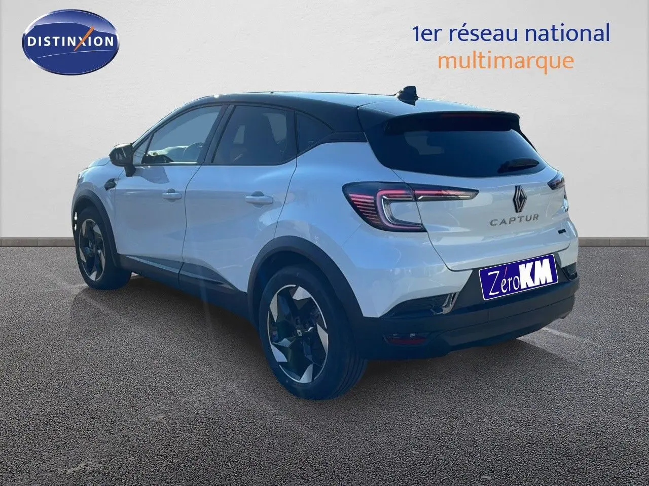 Vue 3/4 arrière droite d'un Renault Captur E-Tech hybride blanc nacré avec toit noir et jantes noires.