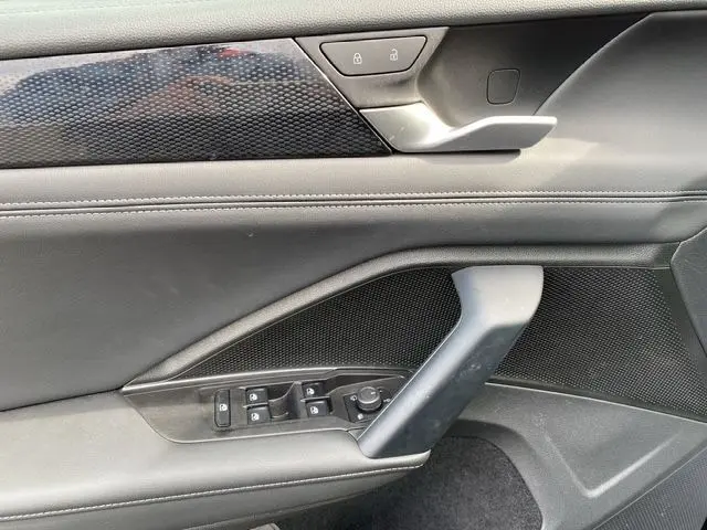Détail de la porte intérieure côté conducteur du Volkswagen Tiguan noir 2024, avec commandes de vitres et verrouillage.