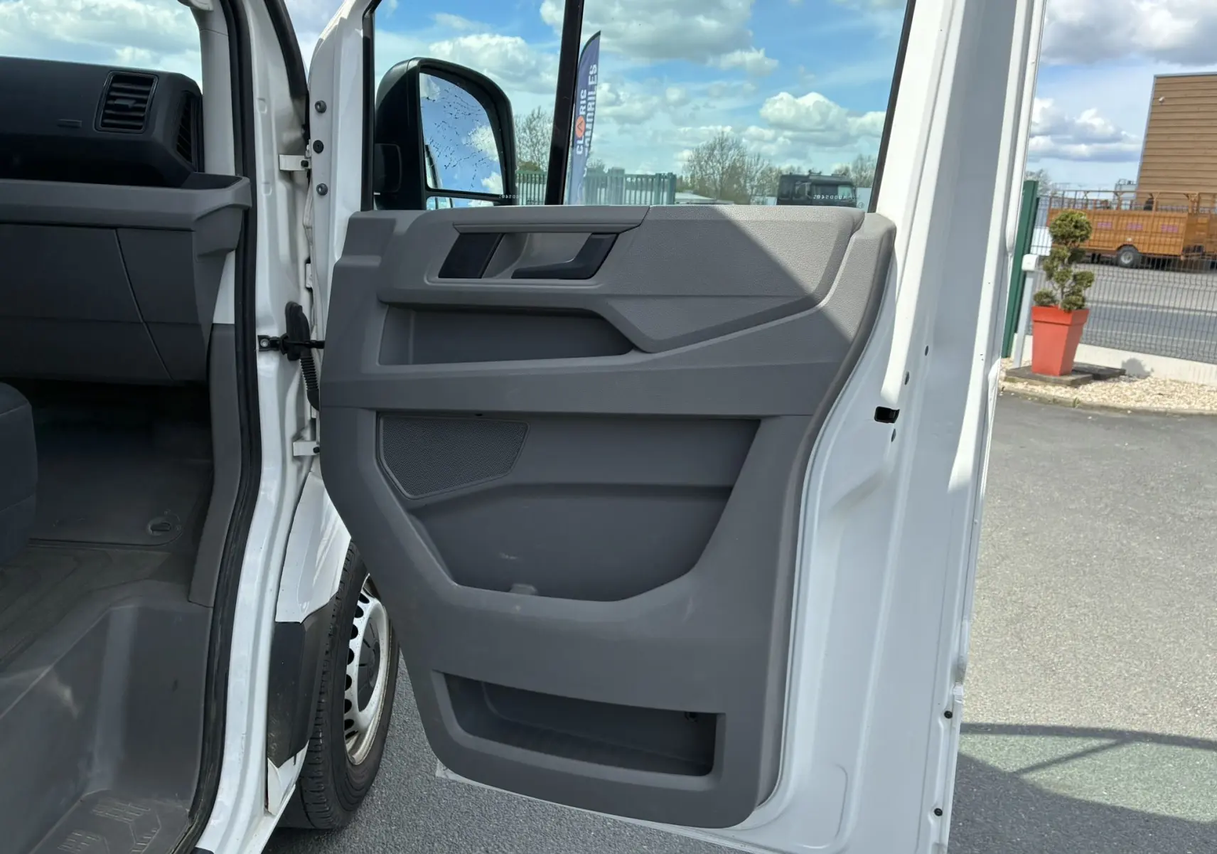 Vue rapprochée de la porte avant droite ouverte du Volkswagen Crafter blanc, montrant le panneau intérieur gris.