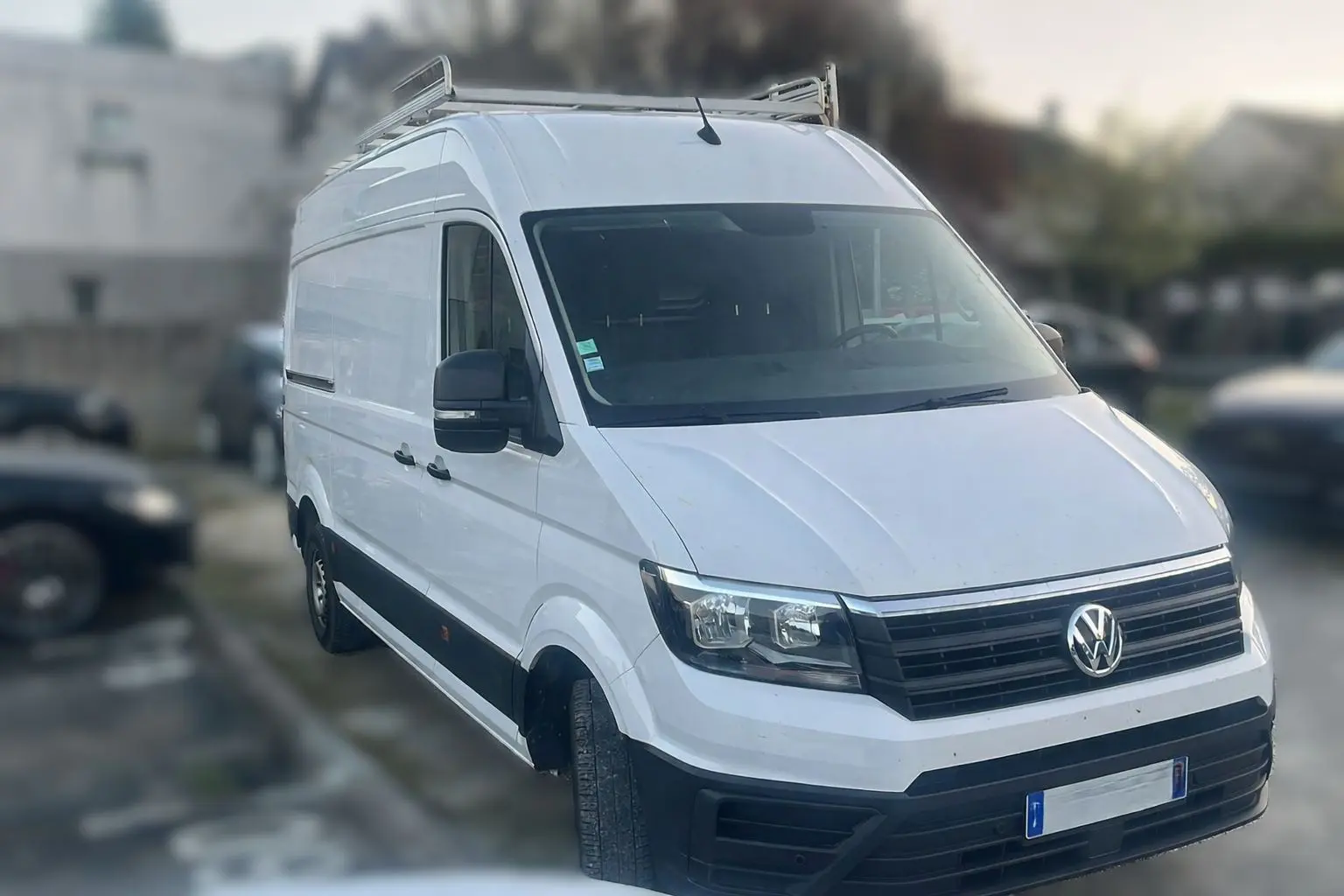 Vue frontale d'un Volkswagen Crafter blanc avec calandre noire et plaque Distinxion visible.