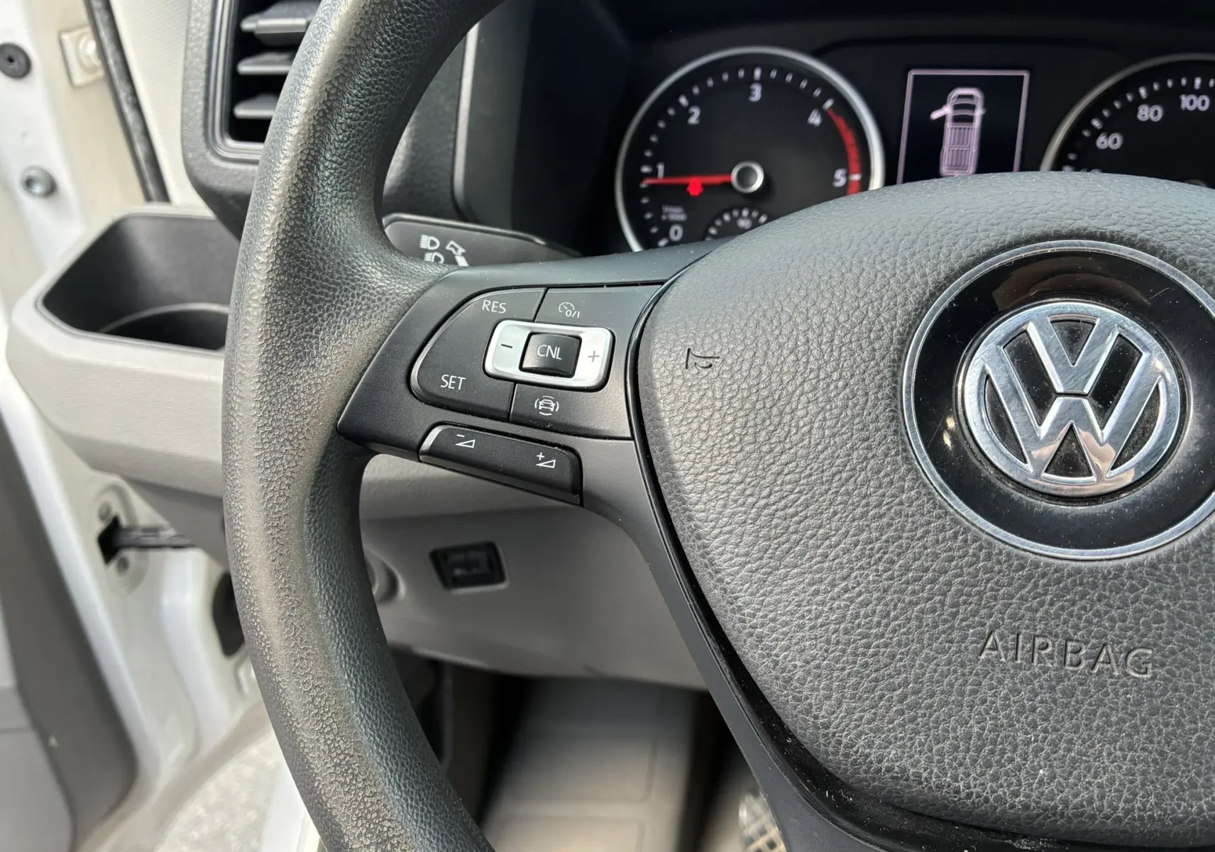 Gros plan sur le volant multifonctions noir et le tableau de bord du Volkswagen Crafter blanc, côté conducteur.