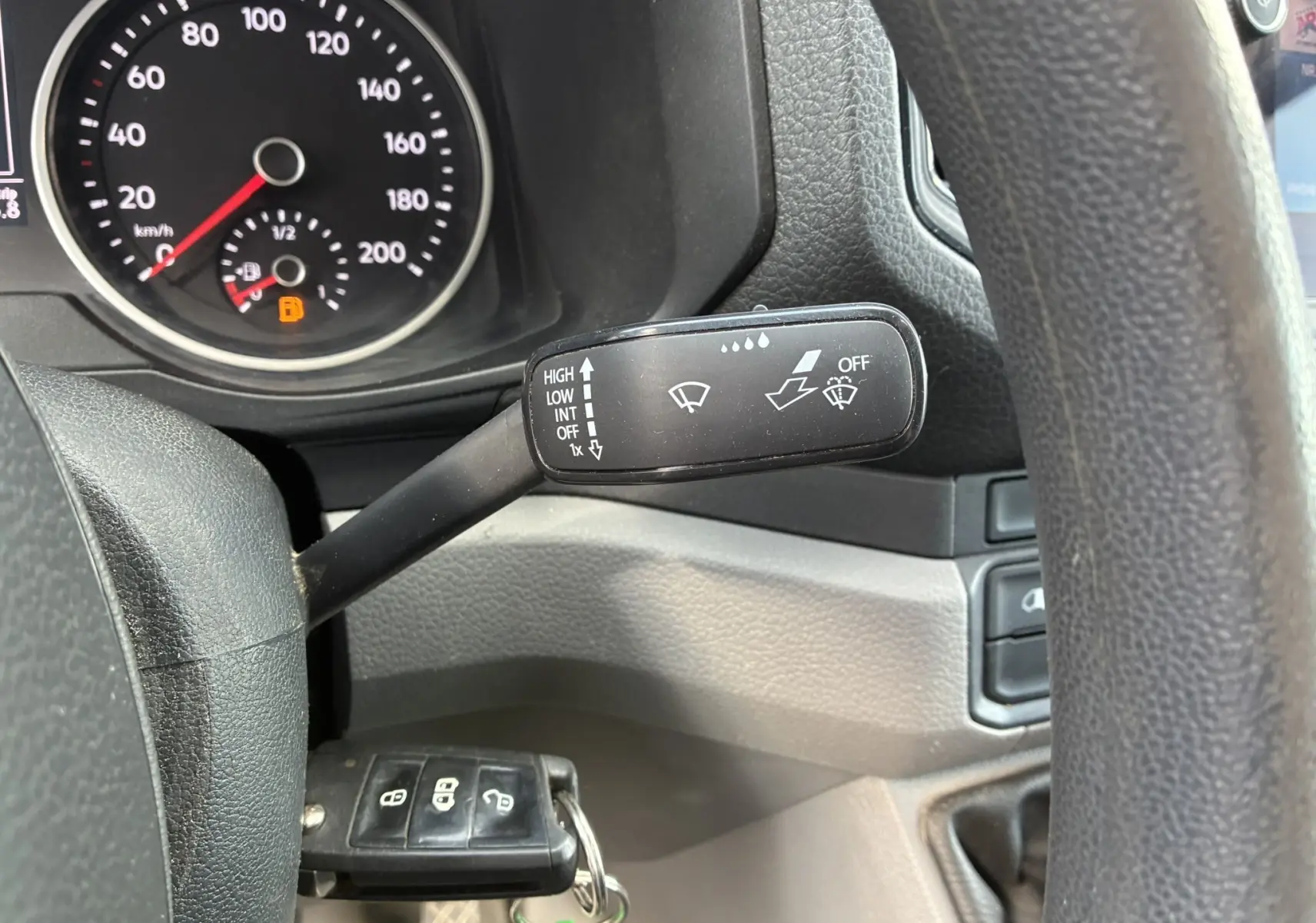 Gros plan sur la manette d’essuie-glace noire à droite du volant dans le tableau de bord du Volkswagen Crafter blanc.