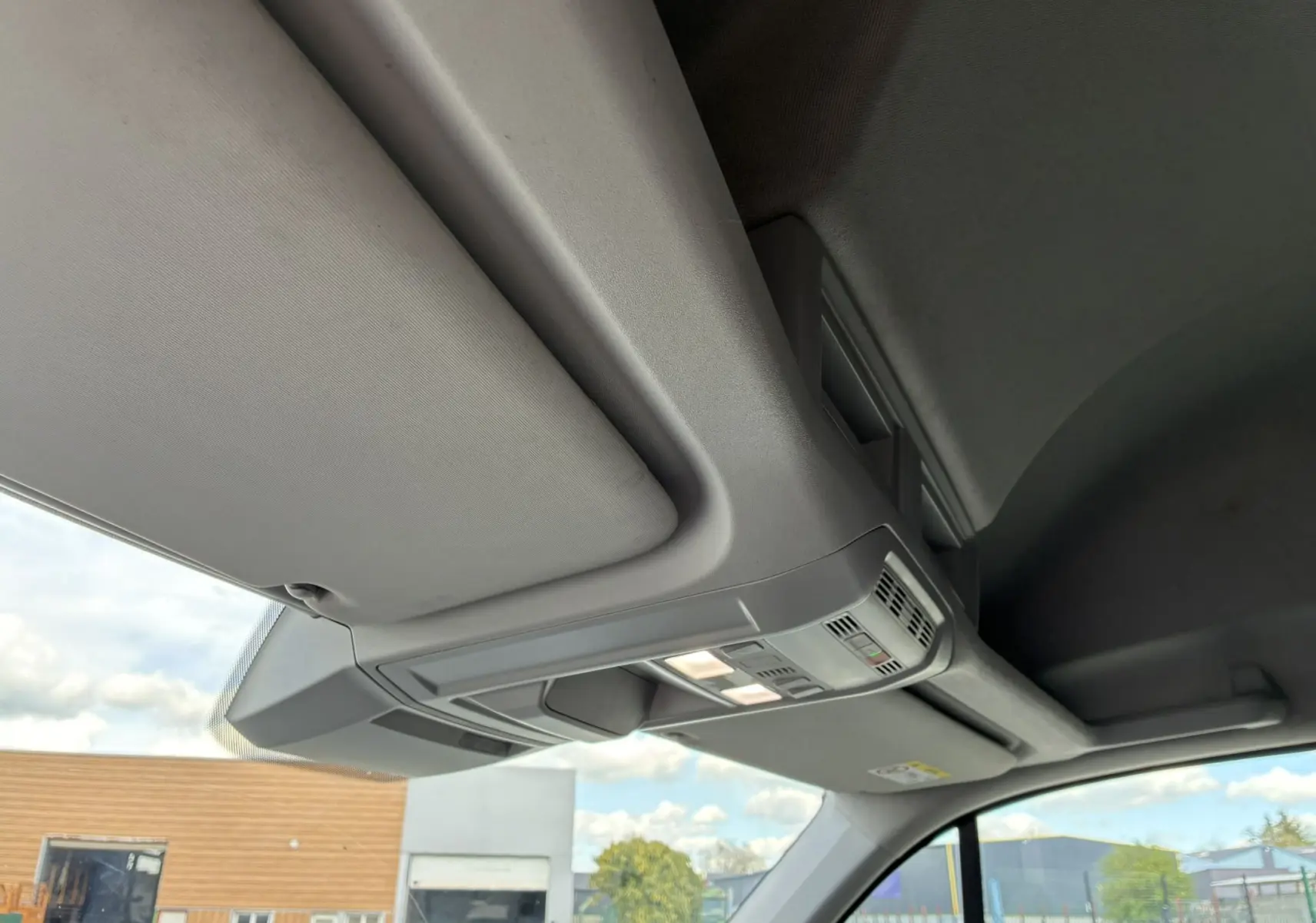 Vue intérieure du plafond avant du Volkswagen Crafter blanc, montrant les commandes d'éclairage et le pare-soleil côté droit.