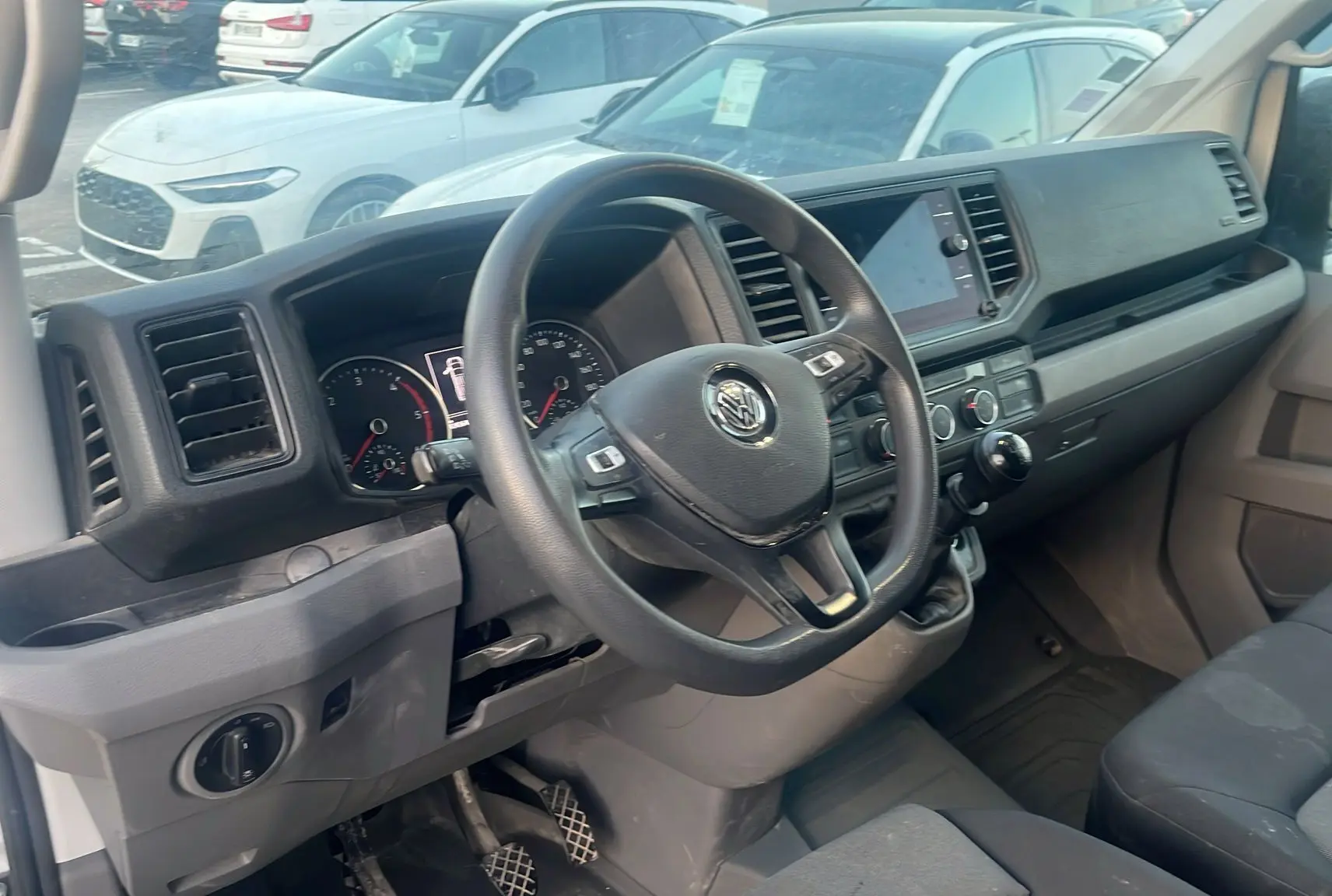 Vue de profil côté droit d'un Volkswagen Crafter blanc avec galerie de toit et double portes arrière ouvertes à 270° visibles en arrière-plan.