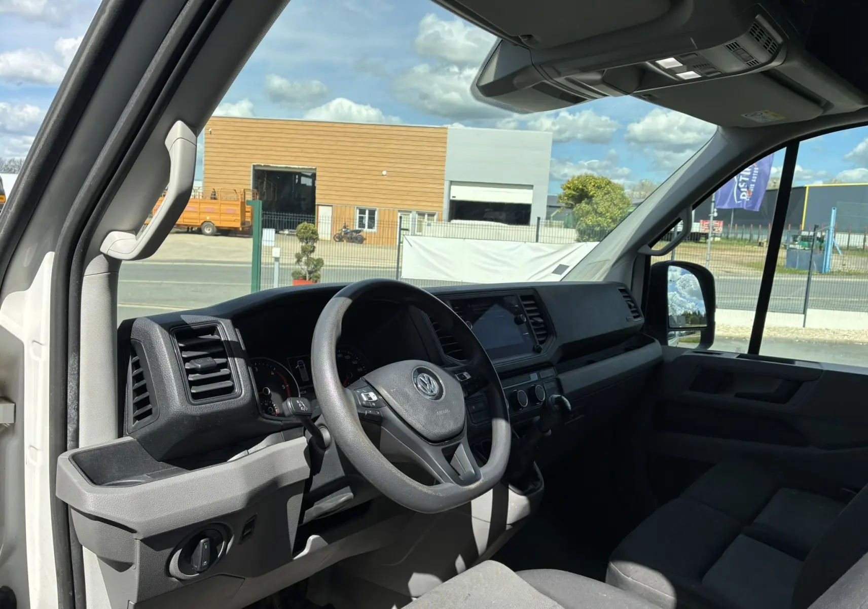 Vue intérieure côté conducteur du Volkswagen Crafter blanc 2020, montrant le volant multifonctions et tableau de bord moderne.